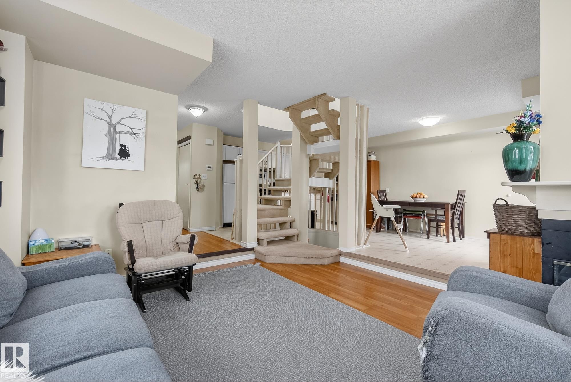 This inviting living area features hardwood flooring, a carpeted floor area, and a fireplace with a mantel - 2006 Mill Woods Road E, Edmonton, AB - Indoor Photo Showing Living Room