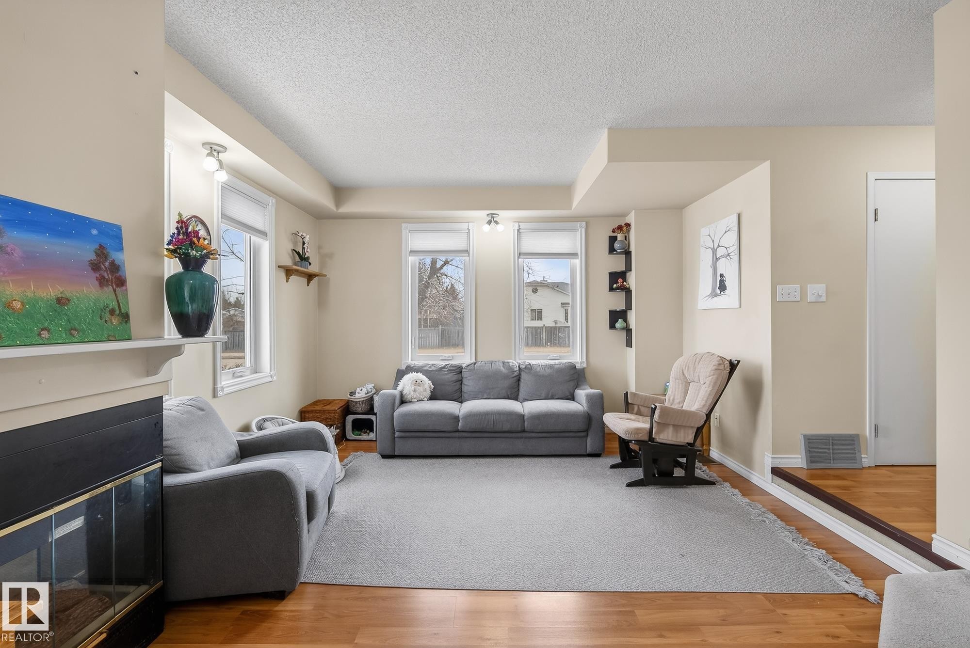 The living area features hardwood flooring, a fireplace with a mantel, and several windows providing natural light - 2006 Mill Woods Road E, Edmonton, AB - Indoor Photo Showing Living Room With Fireplace