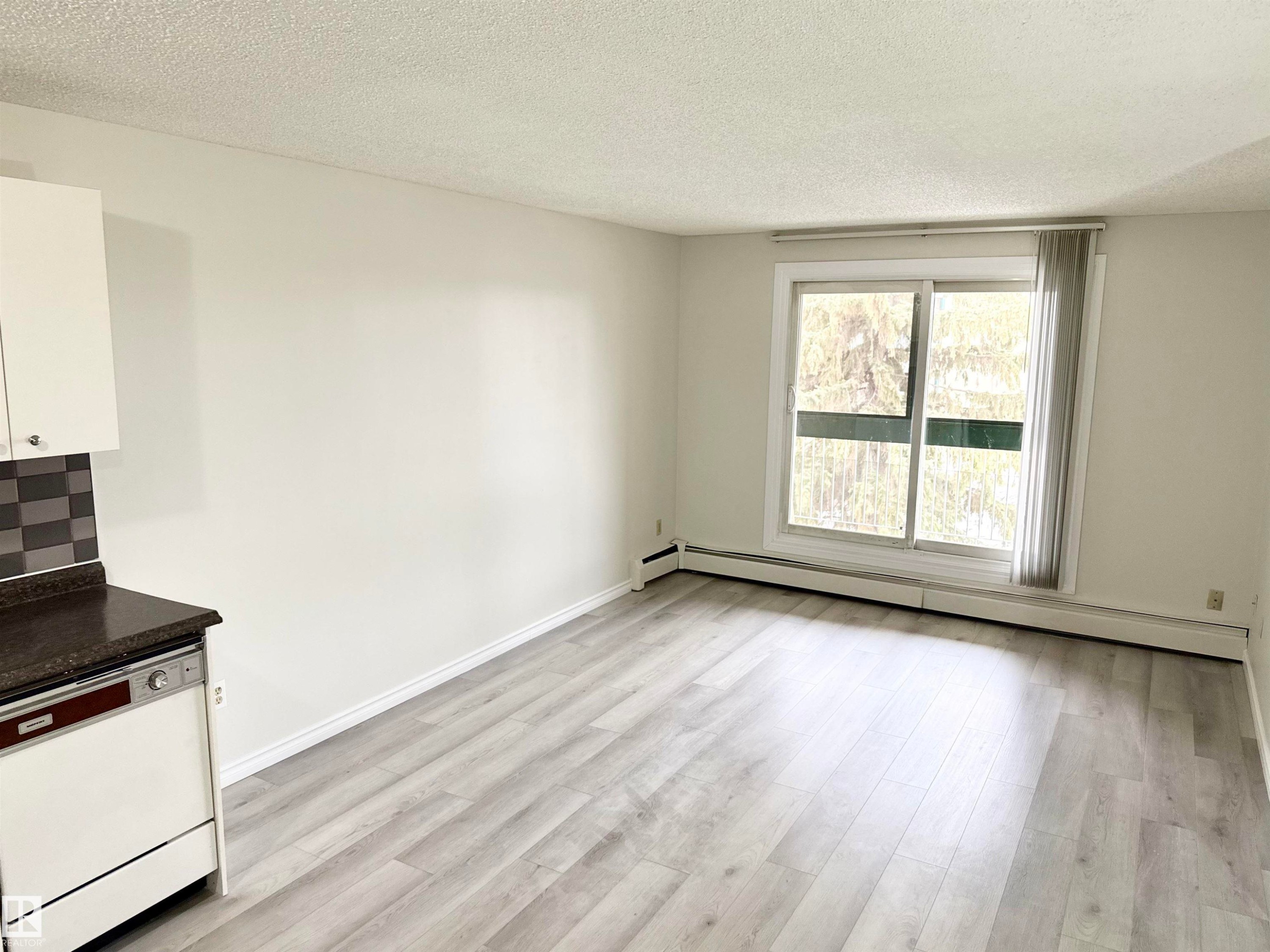 This bright living area features light-colored laminate flooring and a large window, providing natural illumination - 307 1620 48 Street, Edmonton, AB