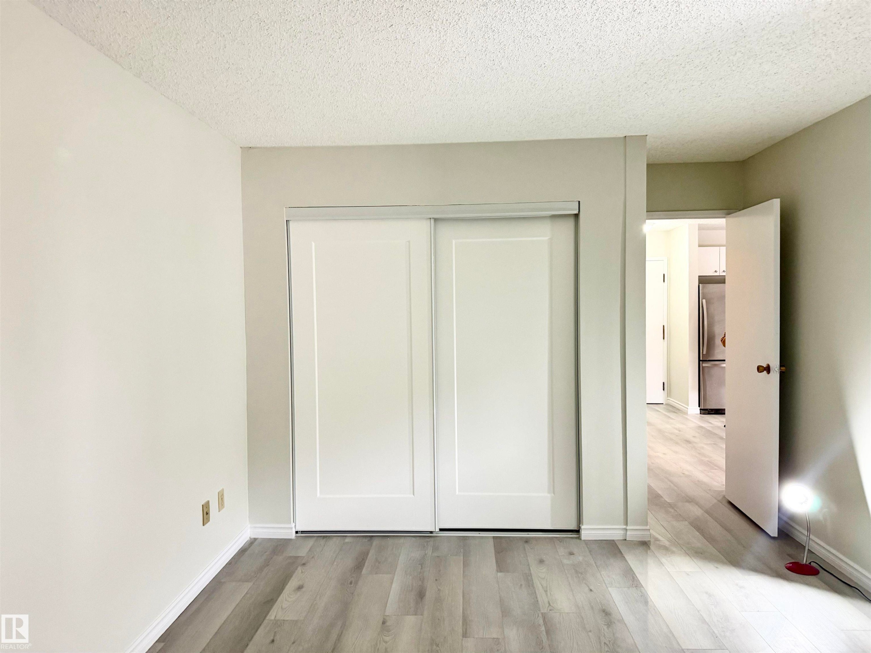 This room features light-colored laminate flooring, white baseboards, and a neutral wall color - 307 1620 48 Street, Edmonton, AB
