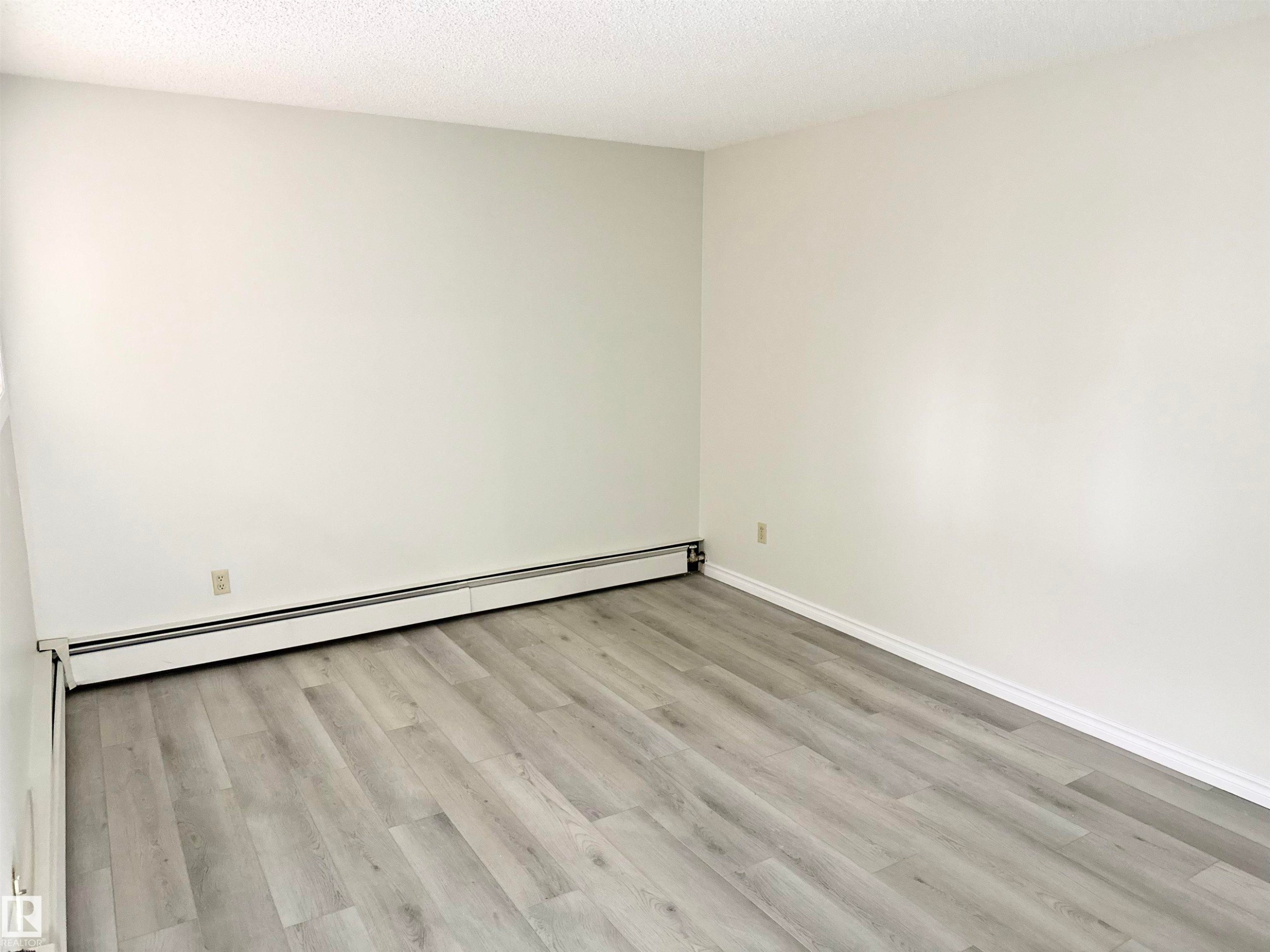 This room features light grey wood-look flooring and white painted walls, creating a bright and neutral aesthetic - 307 1620 48 Street, Edmonton, AB