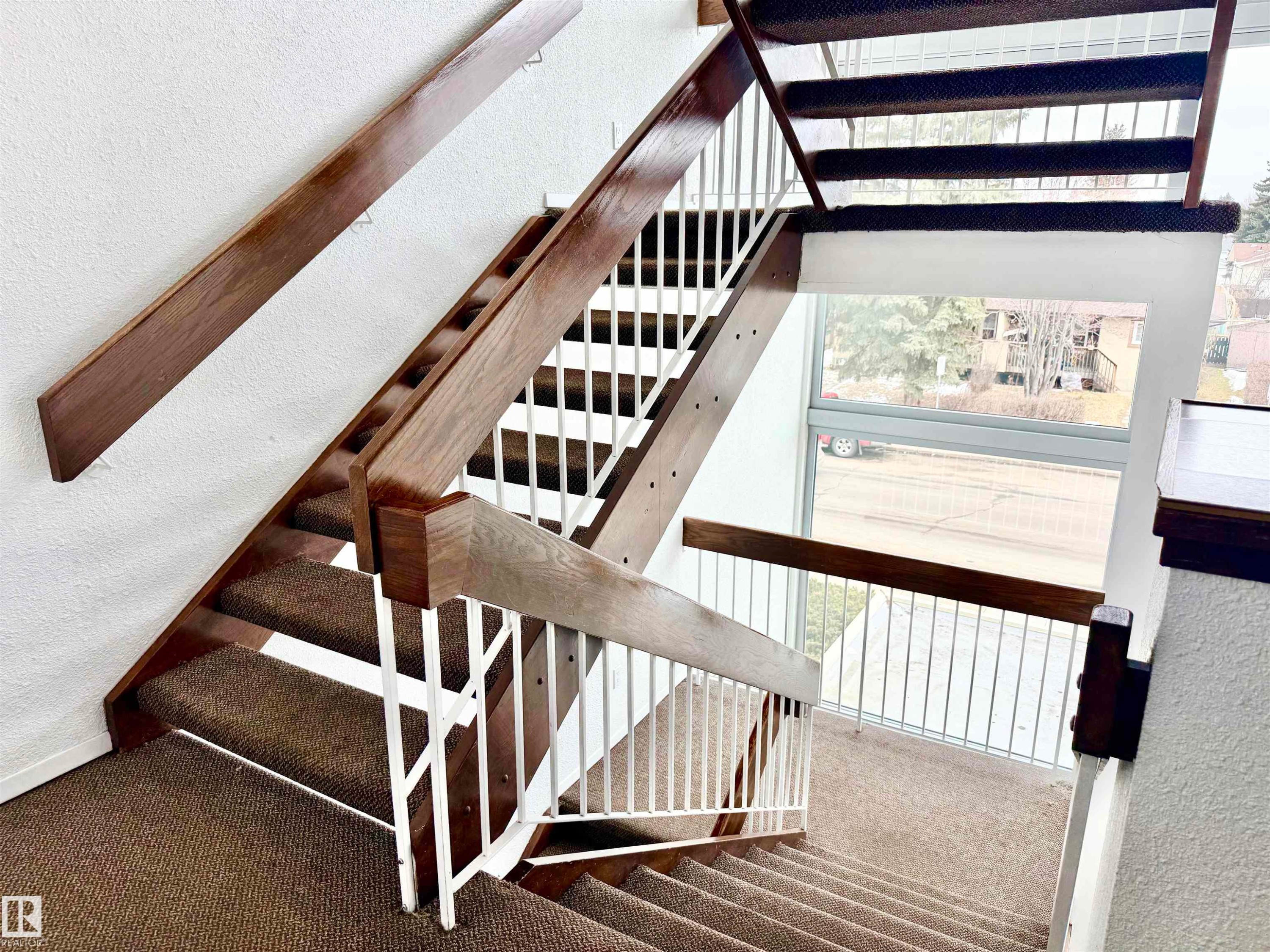 Staircase featuring carpeted treads, white risers, and wooden handrails - 307 1620 48 Street, Edmonton, AB