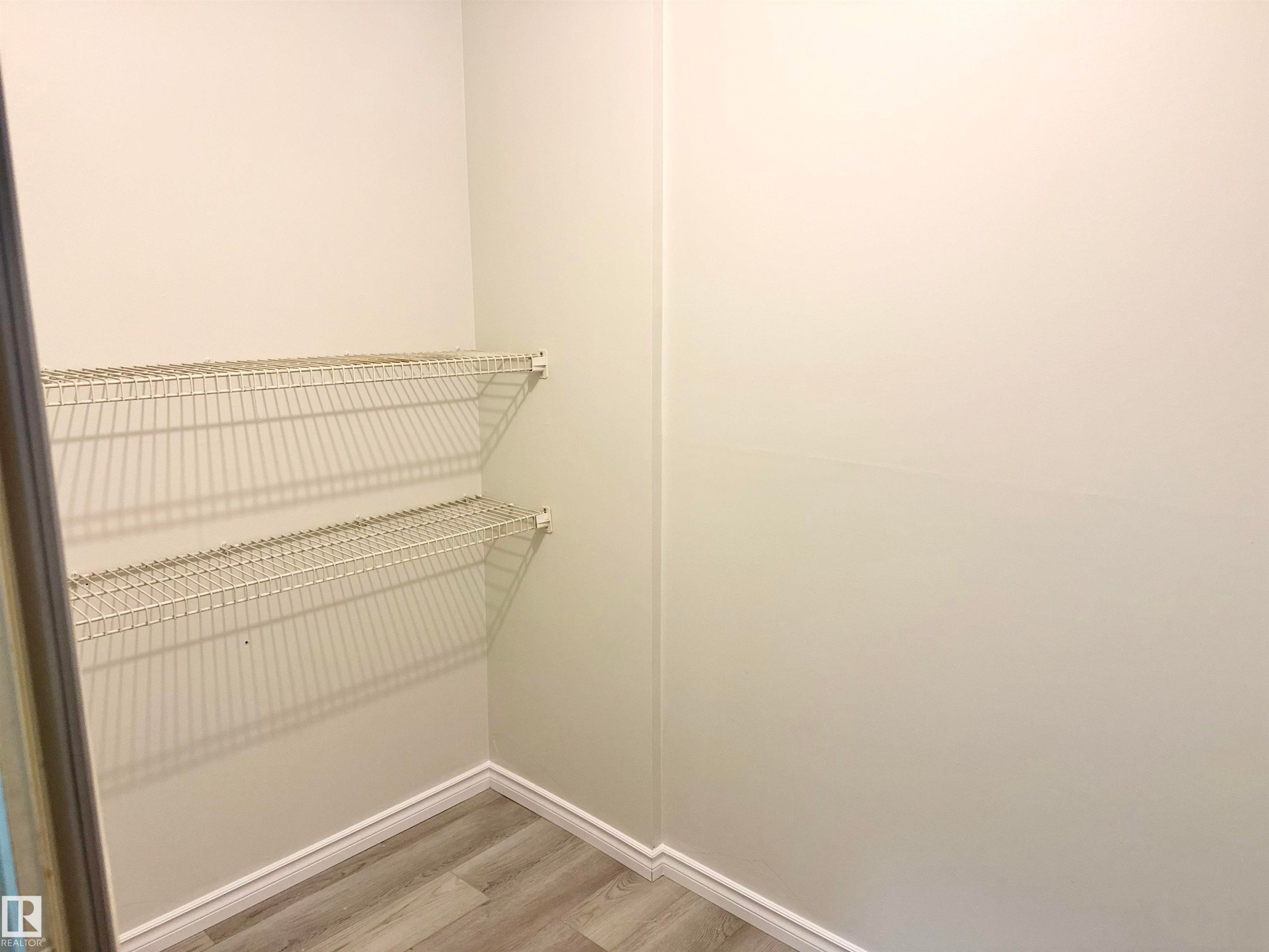 This closet provides convenient storage with two tiers of wire shelving and a light-toned wood-style floor - 307 1620 48 Street, Edmonton, AB