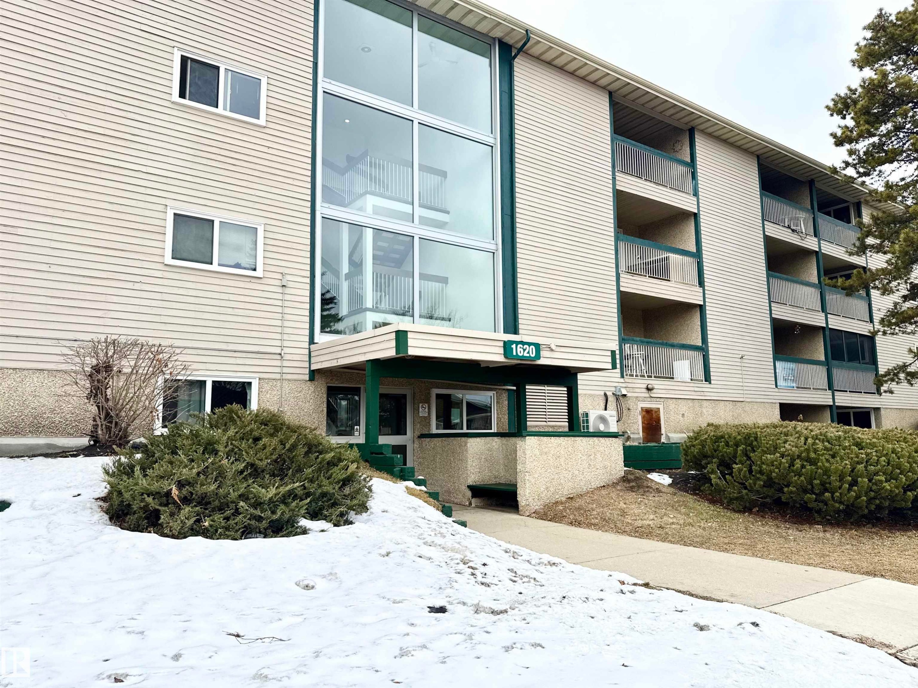 The property features a multi-story building with a light-colored exterior and green trim - 307 1620 48 Street, Edmonton, AB