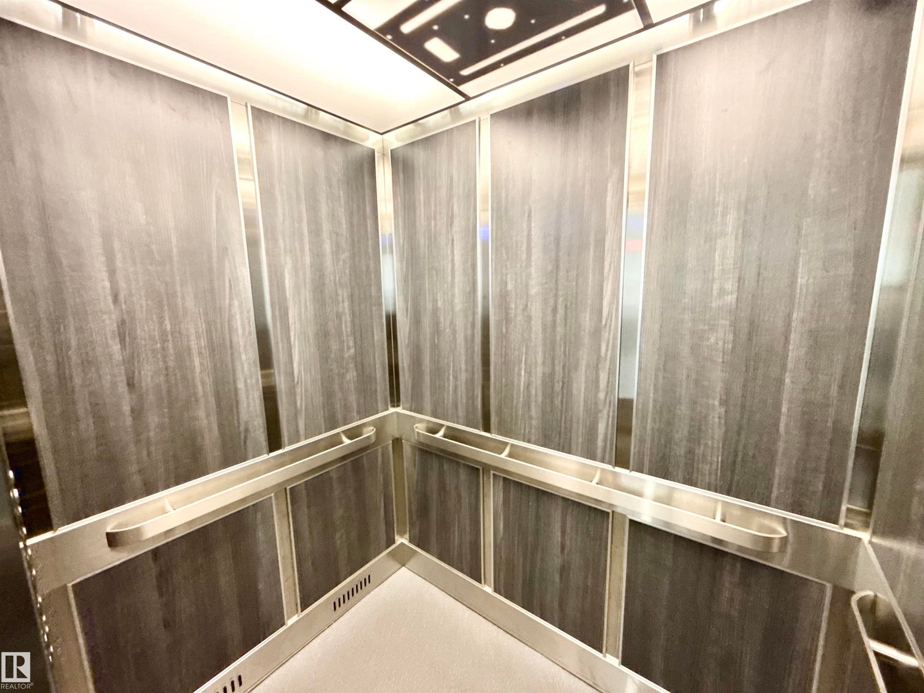 The property features a contemporary elevator with wood paneling and sleek silver accents - 307 1620 48 Street, Edmonton, AB