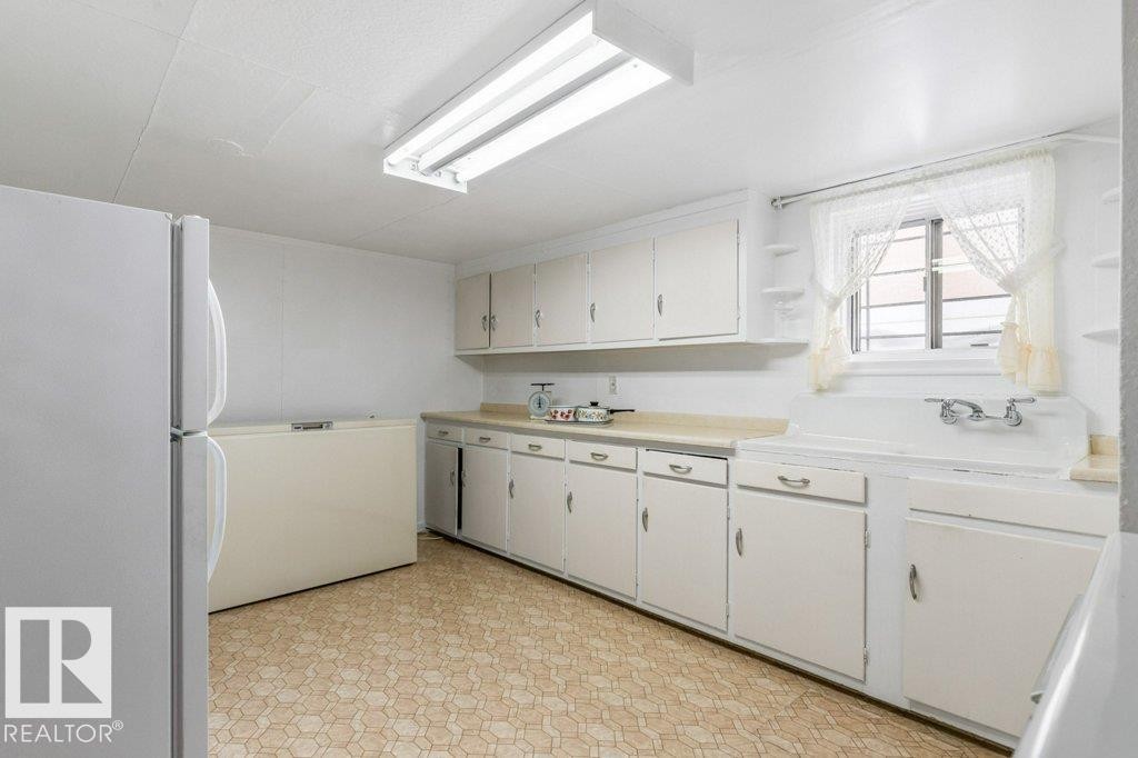 Kitchen with freestanding refrigerator, light flooring, light countertops, white cabinets, and open shelves - 8810 93 Street, Edmonton, AB - Indoor