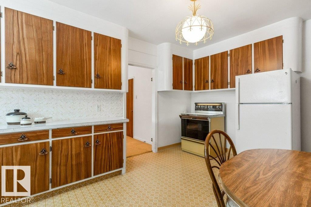 Kitchen with light floors, freestanding refrigerator, electric range oven, brown cabinetry, and light countertops - 8810 93 Street, Edmonton, AB - Indoor Photo Showing Kitchen
