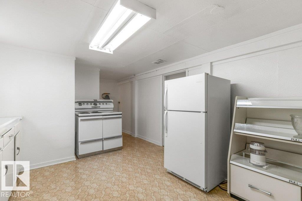 Kitchen featuring white cabinets, light flooring, and white appliances - 8810 93 Street, Edmonton, AB - Indoor Photo Showing Kitchen