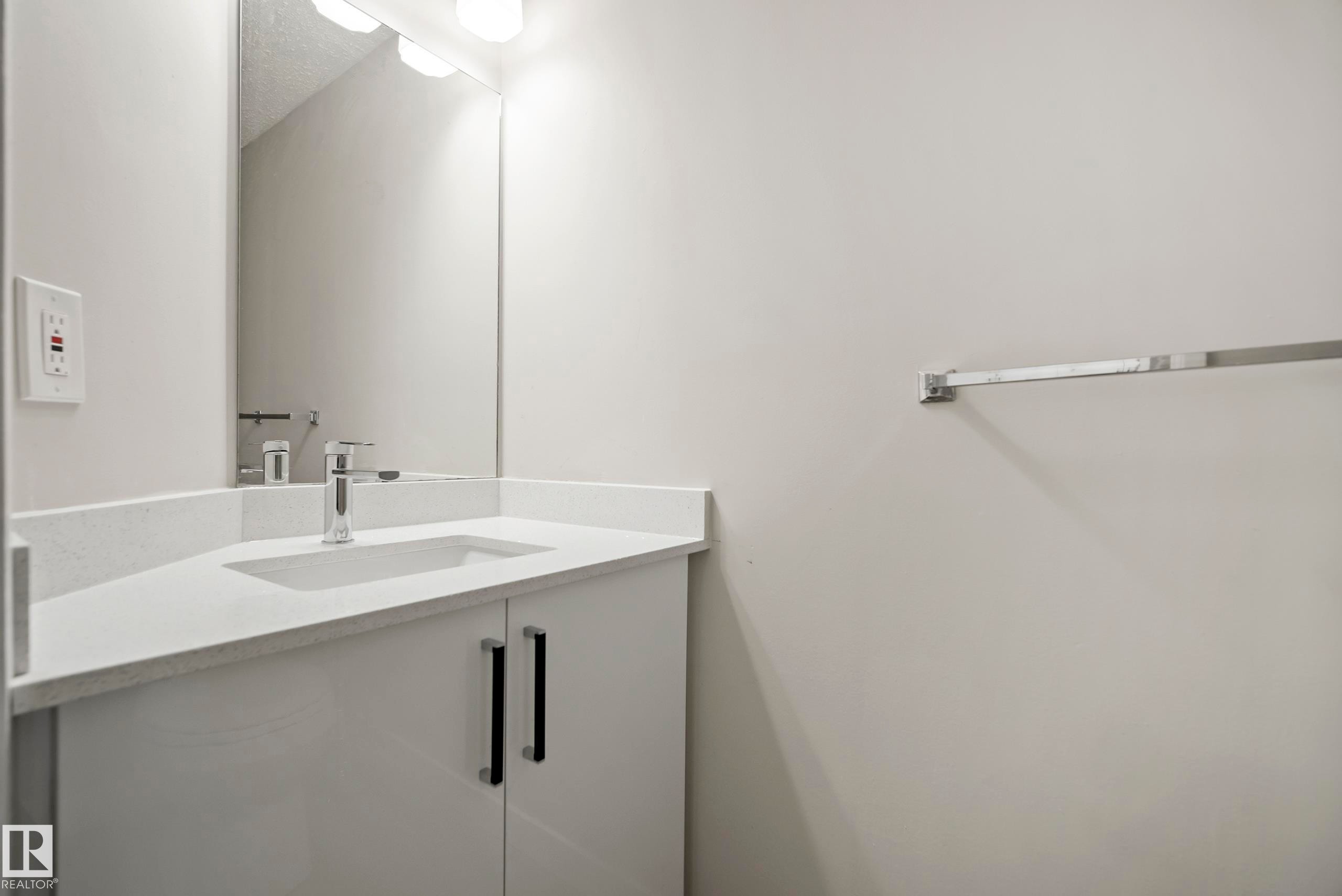 Bathroom featuring a vanity with a white countertop, an integrated sink, and a chrome faucet - 3311 139 Avenue, Edmonton, AB - Indoor Photo Showing Bathroom