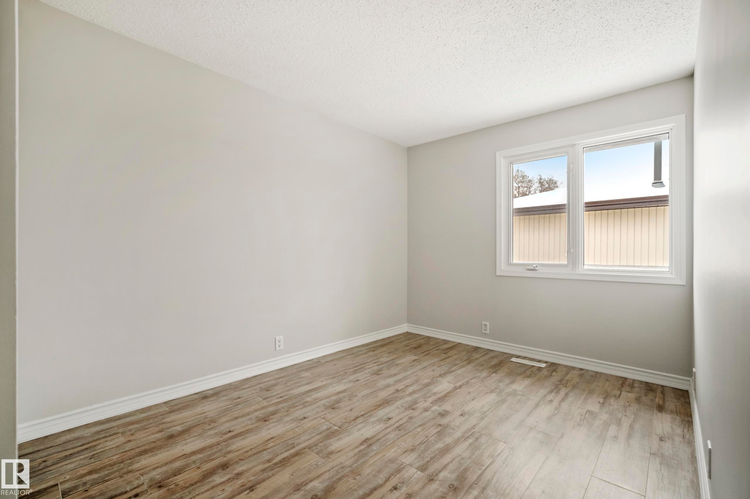 This room features hardwood flooring, light-colored walls, and a window providing natural light - 3311 139 Avenue, Edmonton, AB - Indoor Photo Showing Other Room