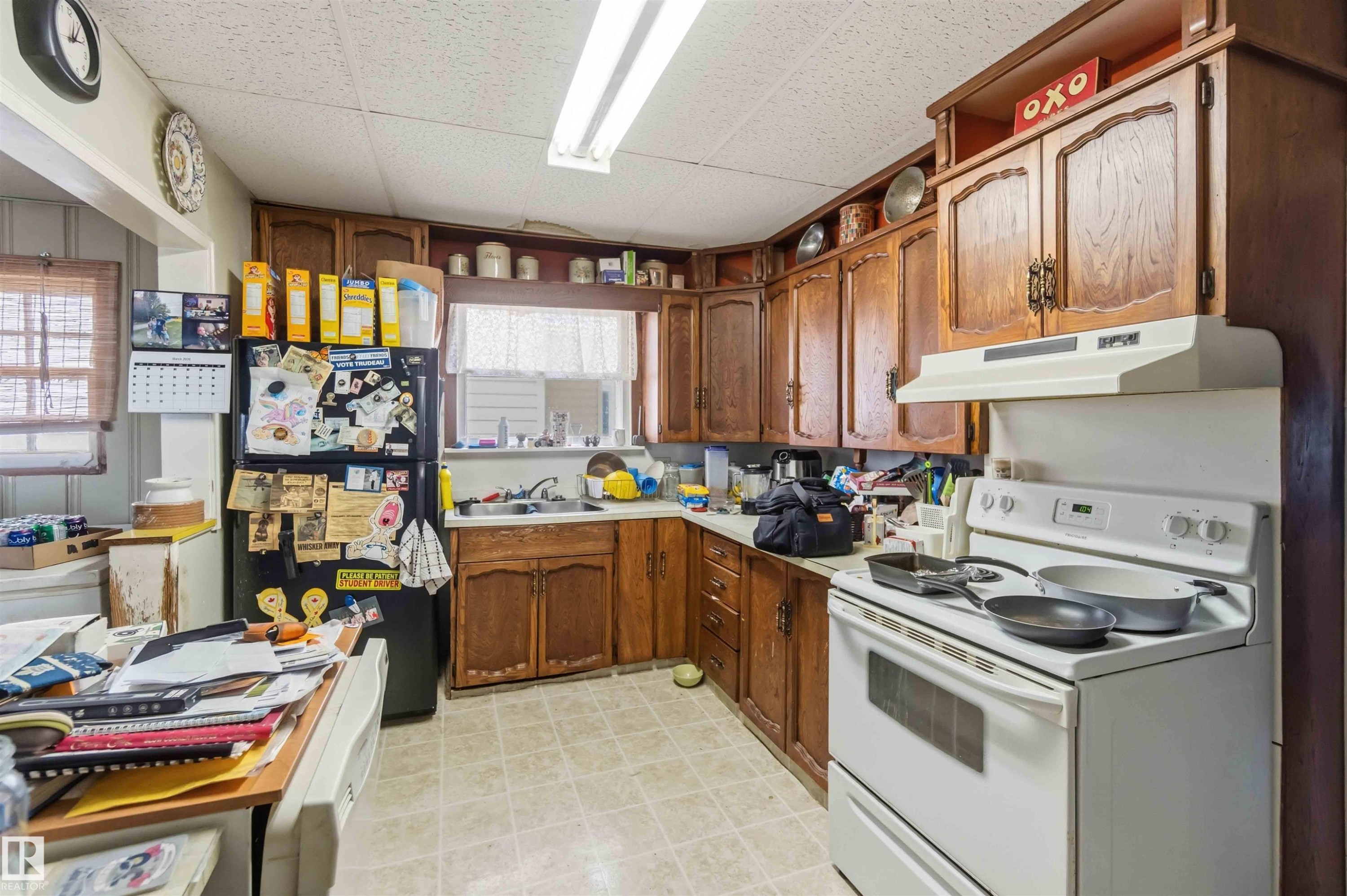 The kitchen features wood cabinetry, a white range with an overhead vent, and a black refrigerator - 10186 143 Street, Edmonton, AB - Indoor Photo Showing Kitchen With Double Sink