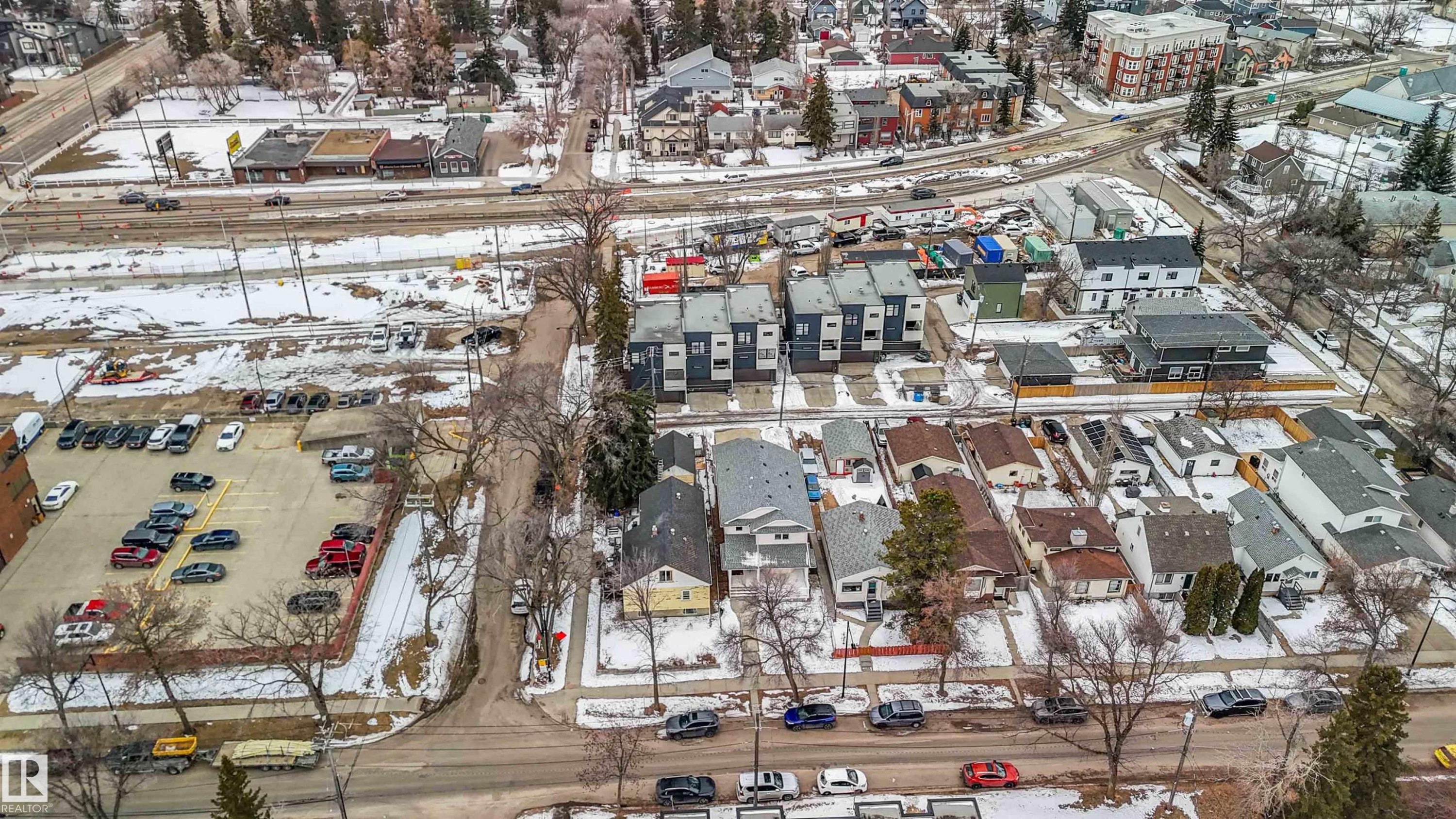 Aerial view showcasing the neighborhood, featuring residential properties, commercial buildings, and a paved parking area - 10186 143 Street, Edmonton, AB - Outdoor With View