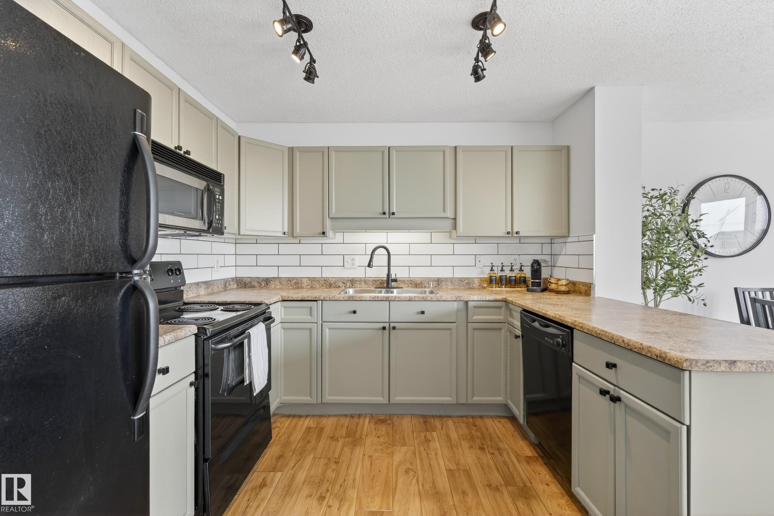 The kitchen features light-colored cabinetry, a white subway tile backsplash, and light wood flooring - 9051 Scott Crescent, Edmonton, AB