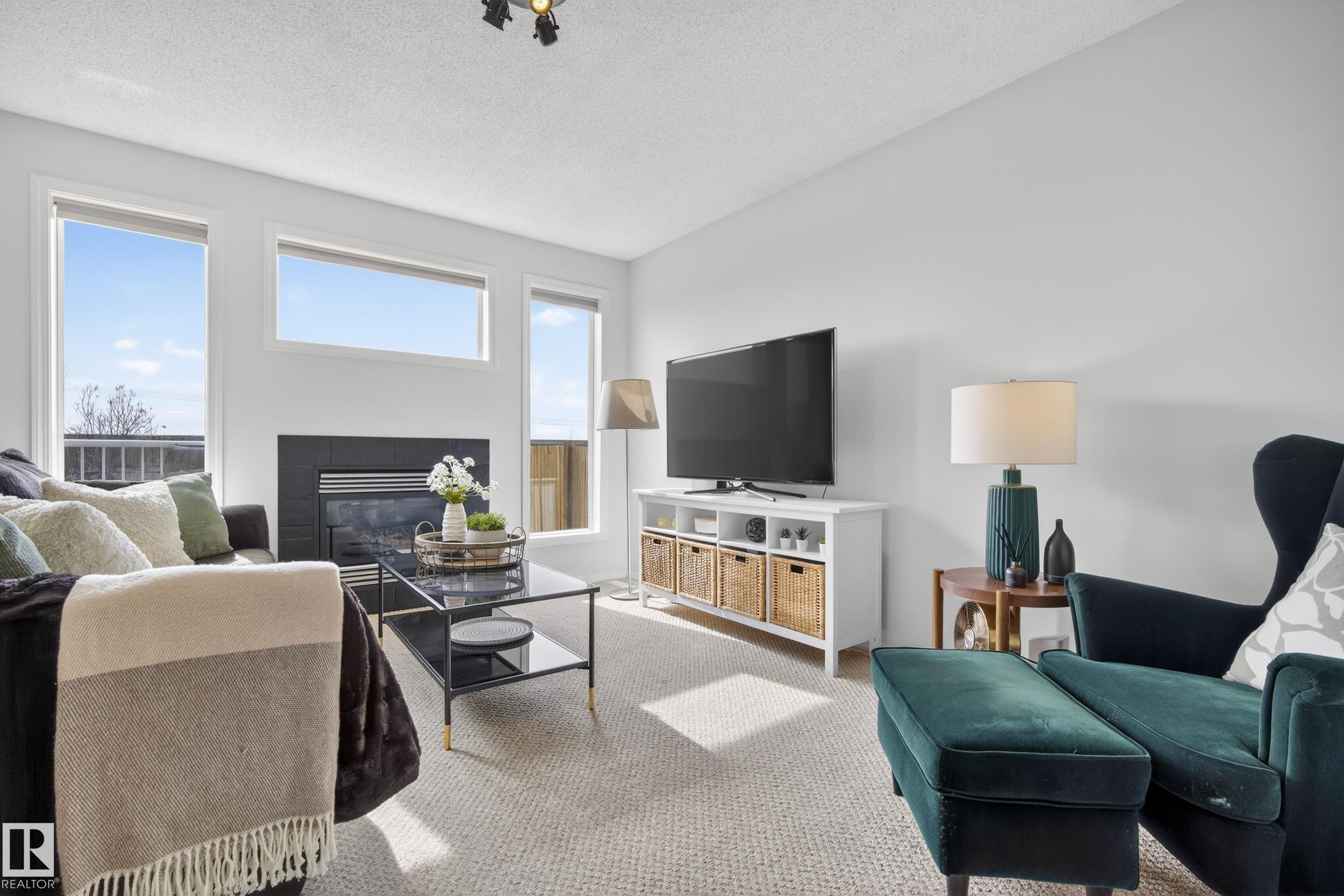 Living room featuring light-colored carpet, a fireplace, and large windows providing natural light - 9051 Scott Crescent, Edmonton, AB