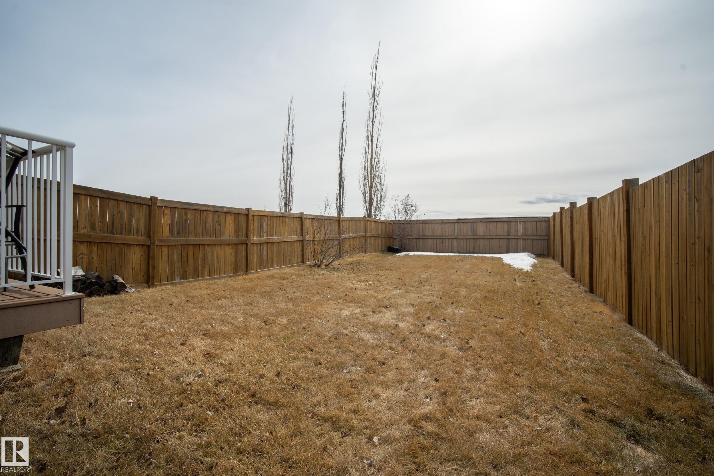 The property features a spacious yard with a wooden fence and a deck with white railings - 9051 Scott Crescent, Edmonton, AB