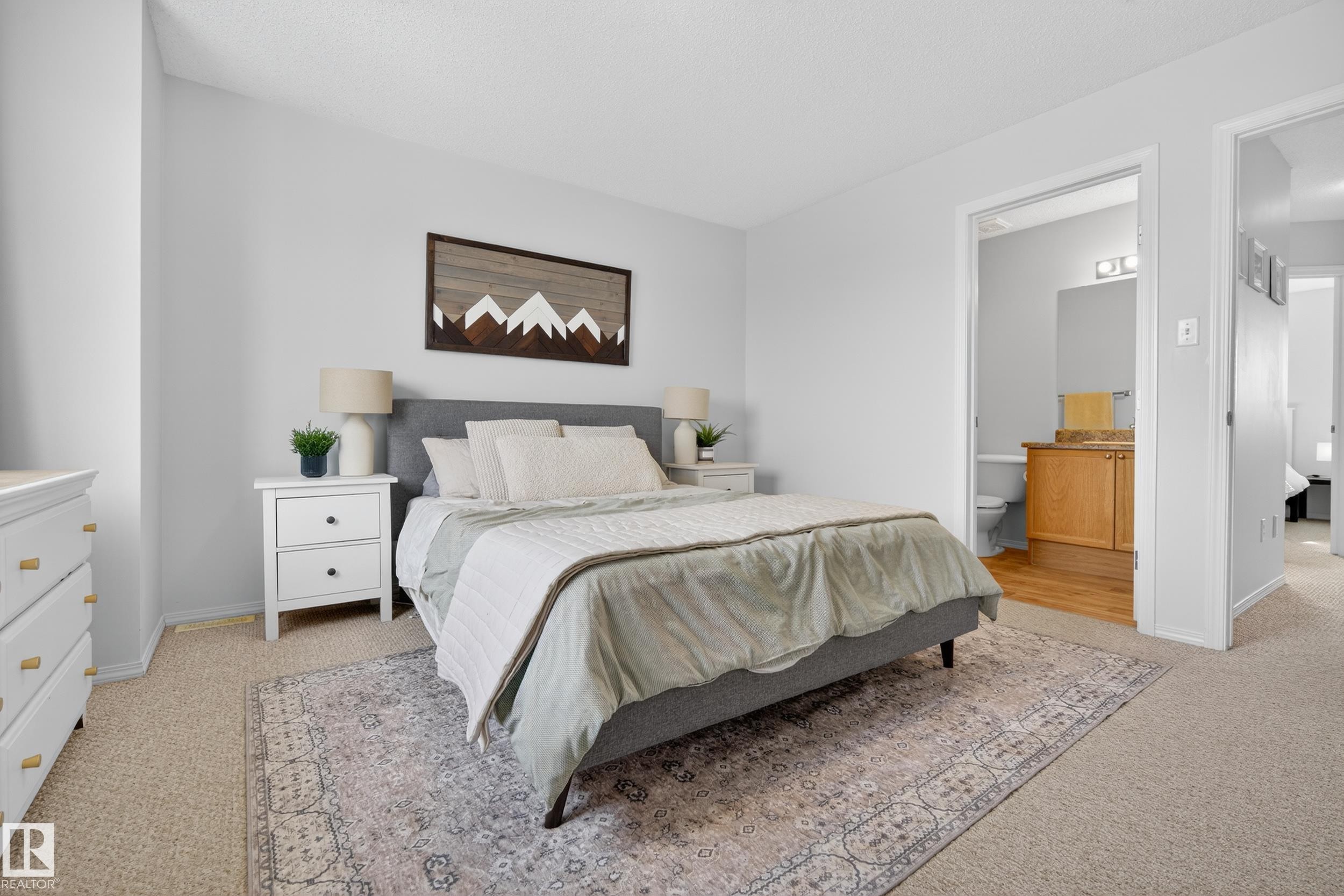 This bedroom features light-colored walls and carpeting, with a patterned area rug - 9051 Scott Crescent, Edmonton, AB