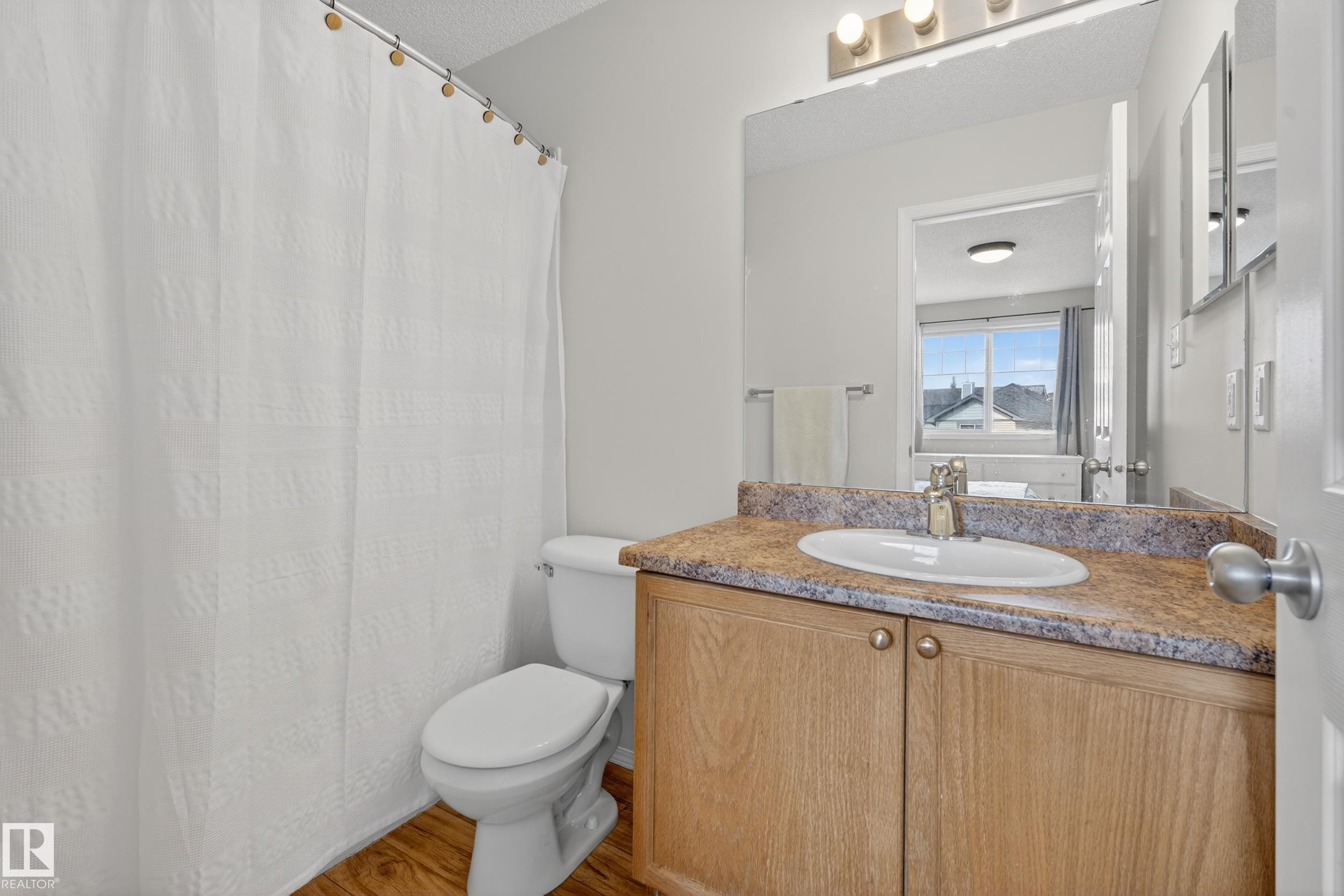 Bright bathroom featuring a vanity with a white basin and a light-colored countertop - 9051 Scott Crescent, Edmonton, AB