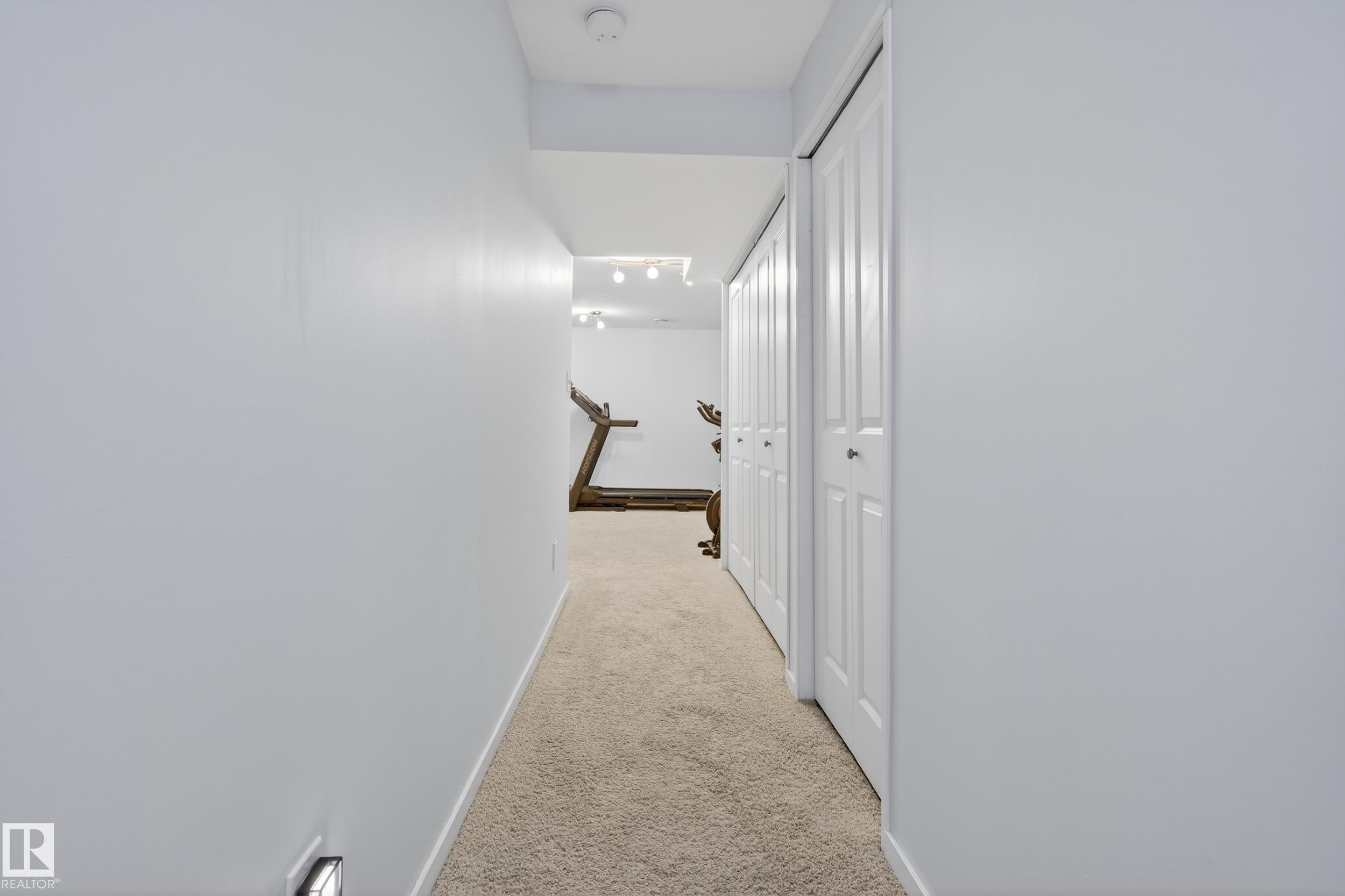 Hallway with light-colored carpet, white walls, and bi-fold closet doors - 9051 Scott Crescent, Edmonton, AB