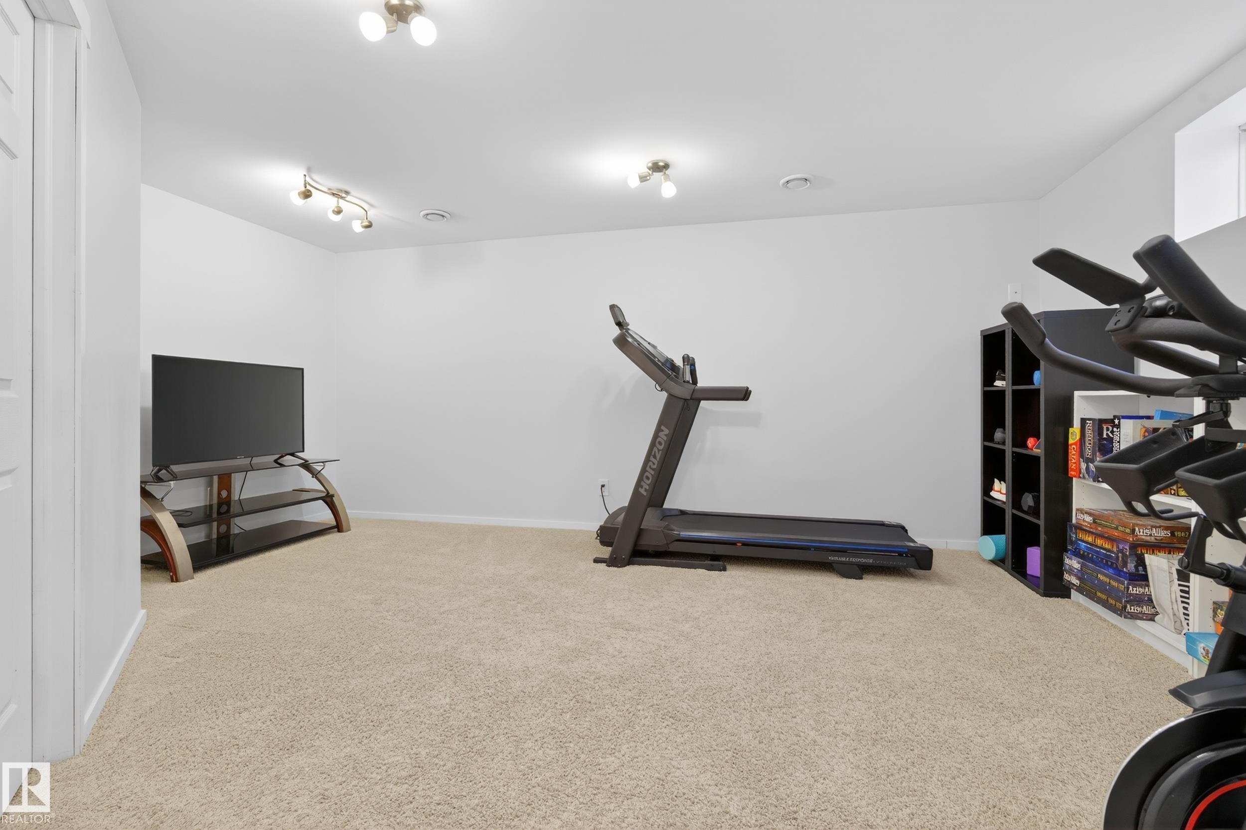 This versatile room offers an expansive carpeted area, light-colored walls, and recessed lighting, providing an adaptable space for various uses - 9051 Scott Crescent, Edmonton, AB