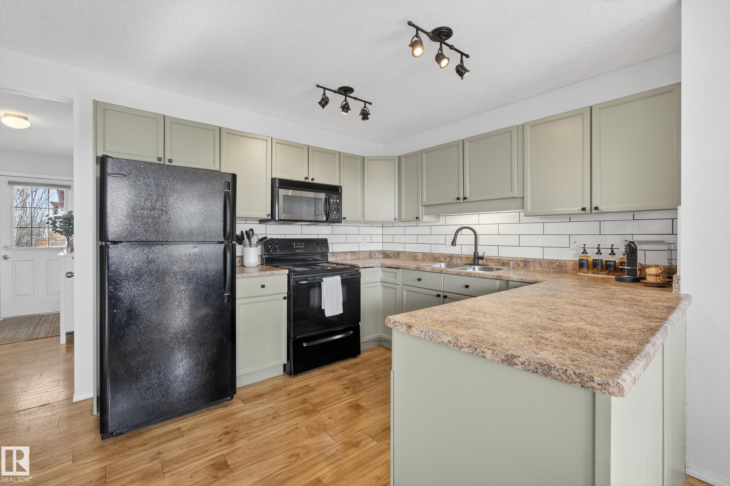 The kitchen features light-colored cabinetry, a white subway tile backsplash, and light-toned countertops - 9051 Scott Crescent, Edmonton, AB