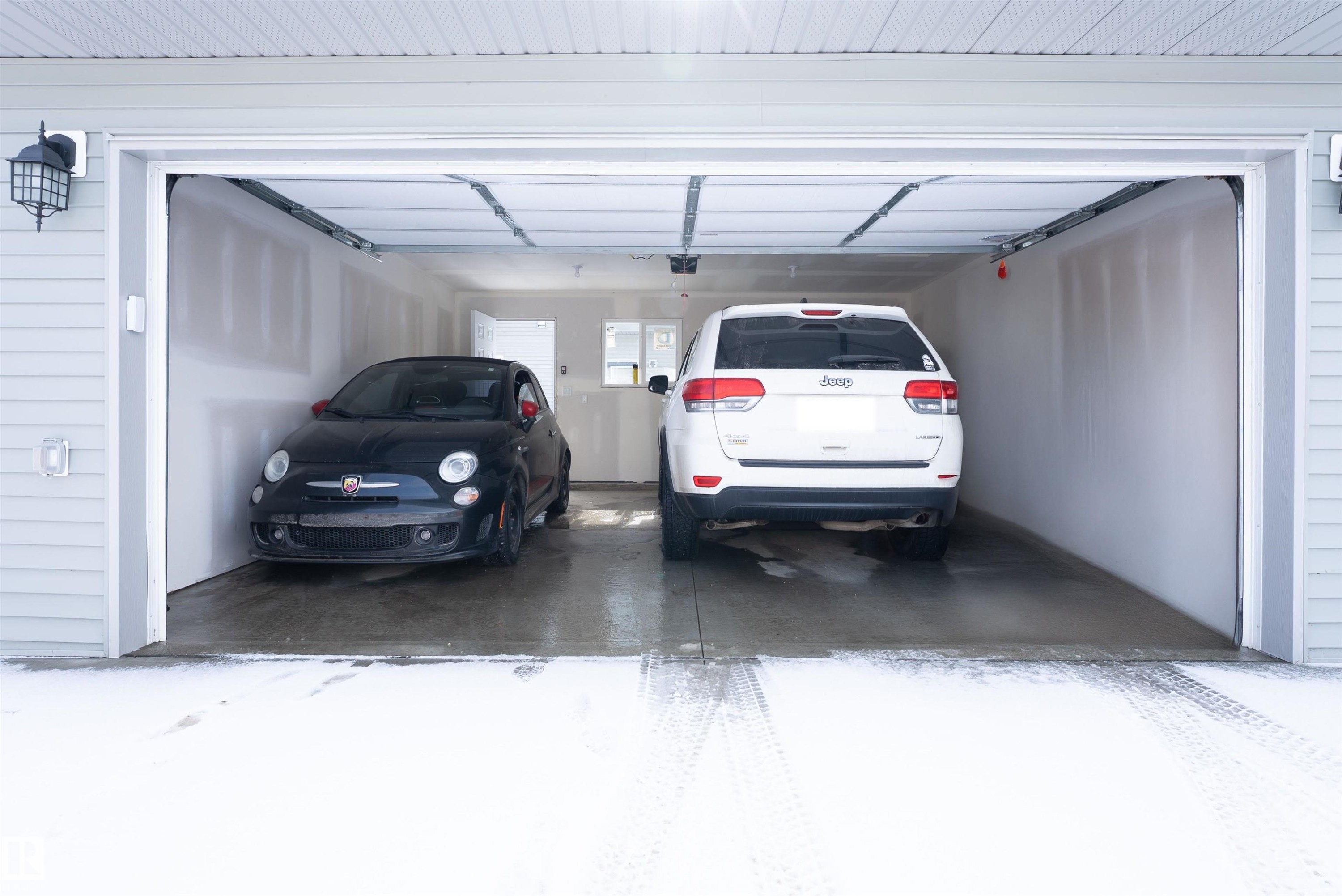 The property features an attached garage with space for at least two vehicles, finished walls, and an overhead garage door - 656 Black Stone, Leduc, AB - Indoor Photo Showing Garage