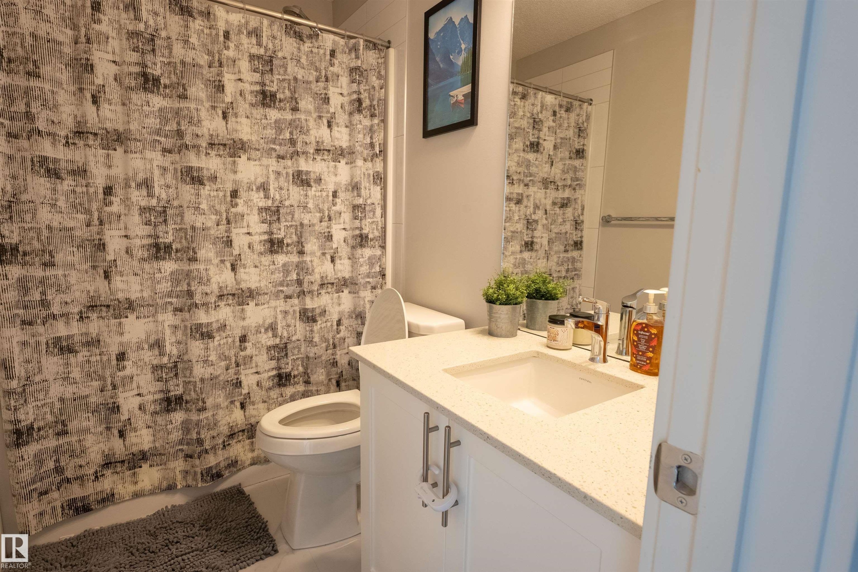 The bathroom features a modern vanity with a white countertop and an undermount sink - 656 Black Stone, Leduc, AB - Indoor Photo Showing Bathroom