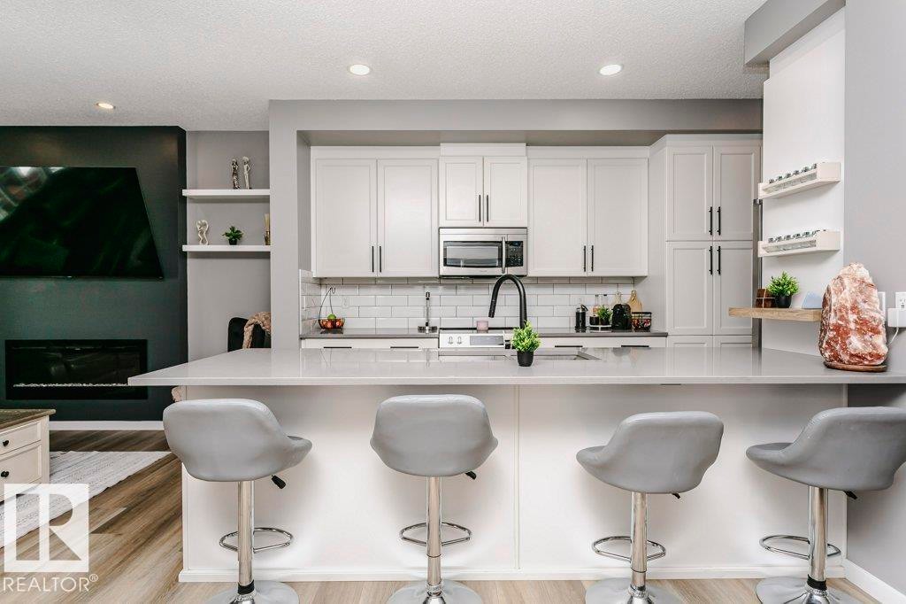 Well-appointed kitchen featuring light-colored cabinetry, a subway tile backsplash, and stainless steel appliances - 320 Balsam Link, Leduc, AB - Indoor Photo Showing Kitchen With Upgraded Kitchen