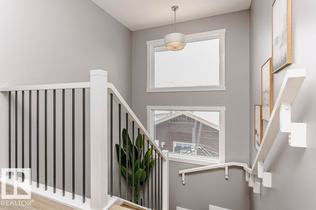 Staircase featuring white railings with black spindles, light grey walls, and windows providing natural light - 320 Balsam Link, Leduc, AB - Indoor Photo Showing Other Room