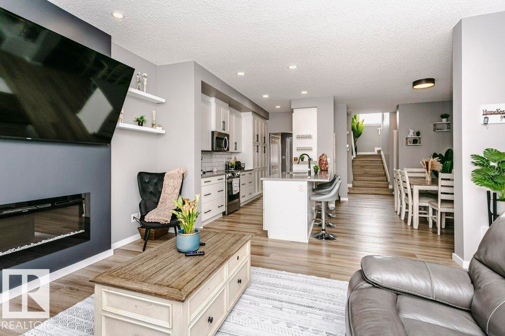Open concept living area featuring light wood flooring, a modern fireplace, and recessed lighting - 320 Balsam Link, Leduc, AB - Indoor Photo Showing Living Room With Fireplace