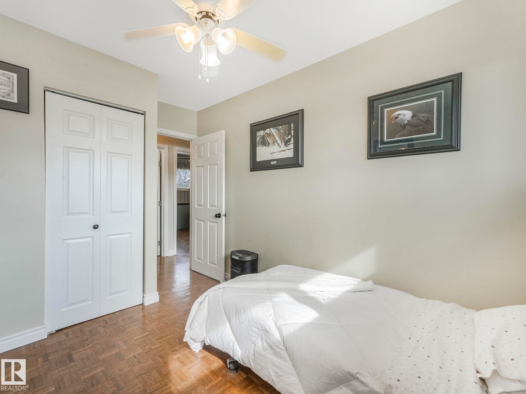 This room features parquet flooring, a ceiling fan with integrated lighting, and white bi-fold closet doors - 16106 79A Avenue Nw, Edmonton, AB - Indoor Photo Showing Bedroom