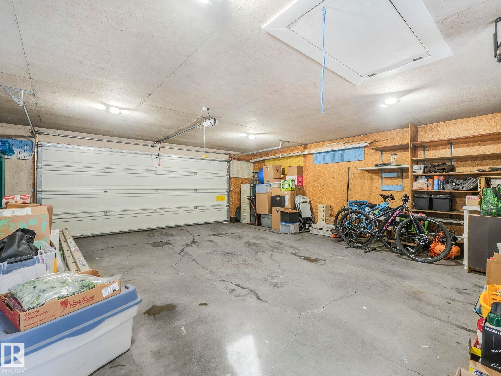 The property features a garage with a roll-up door, exposed ceiling, and integrated lighting - 16106 79A Avenue Nw, Edmonton, AB - Indoor Photo Showing Garage