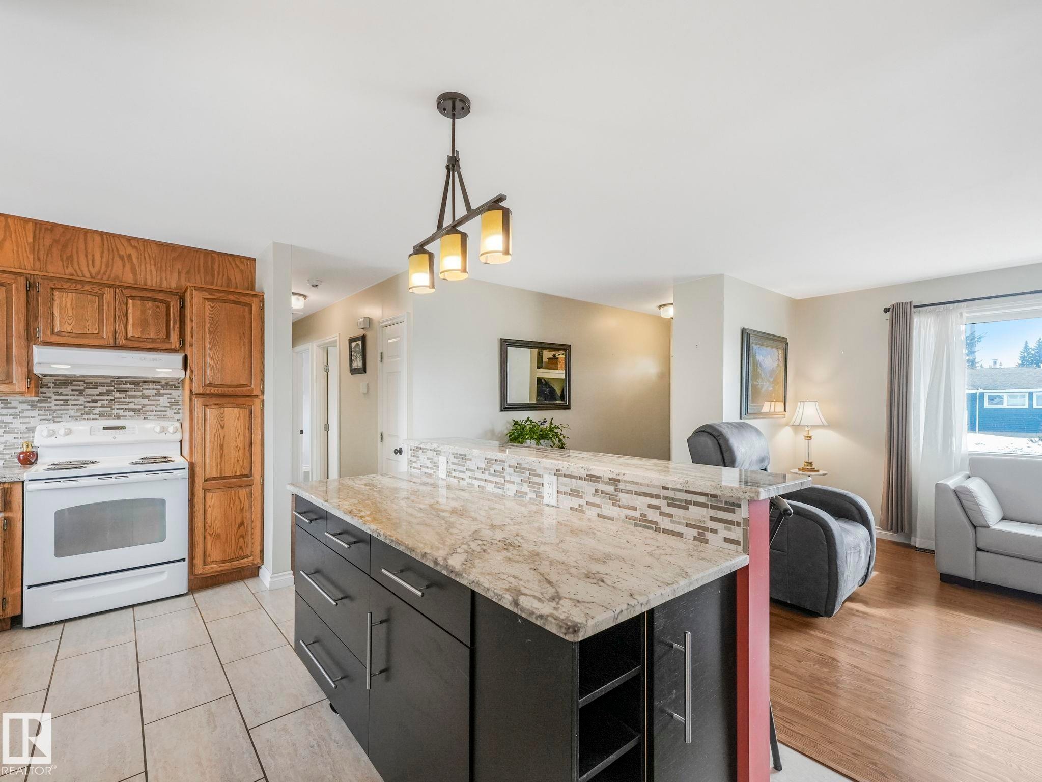 The kitchen features light-toned wooden cabinetry, a white range, and a tiled backsplash - 16106 79A Avenue Nw, Edmonton, AB - Indoor Photo Showing Kitchen