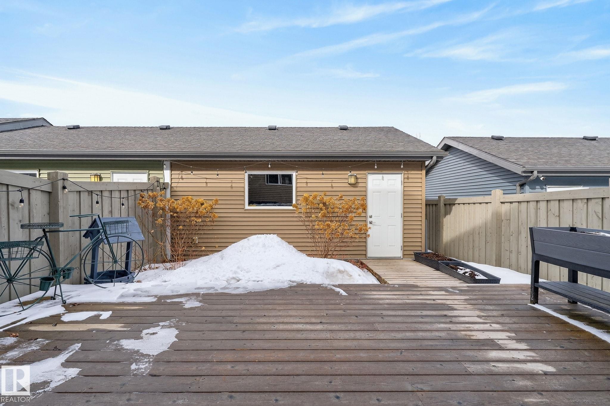 The property features a wooden deck, a light brown exterior, and a white door leading to the building - 9084 Rosenthal Link, Edmonton, AB - Outdoor With Deck Patio Veranda With Exterior