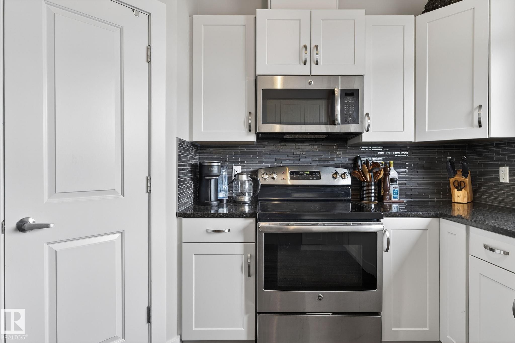 Well-appointed kitchen featuring white cabinetry, stainless steel appliances, dark granite countertops, and a subway tile backsplash - 9084 Rosenthal Link, Edmonton, AB - Indoor Photo Showing Kitchen With Stainless Steel Kitchen With Upgraded Kitchen