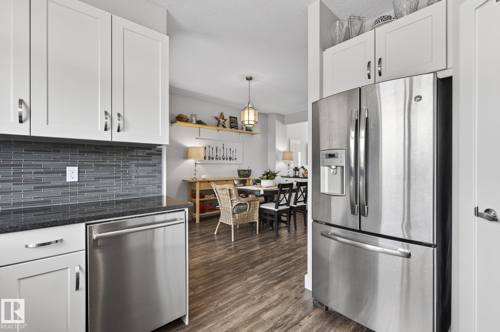 Kitchen featuring white cabinetry, a grey tile backsplash, stainless steel appliances, and dark countertops - 9084 Rosenthal Link, Edmonton, AB - Indoor Photo Showing Kitchen With Stainless Steel Kitchen