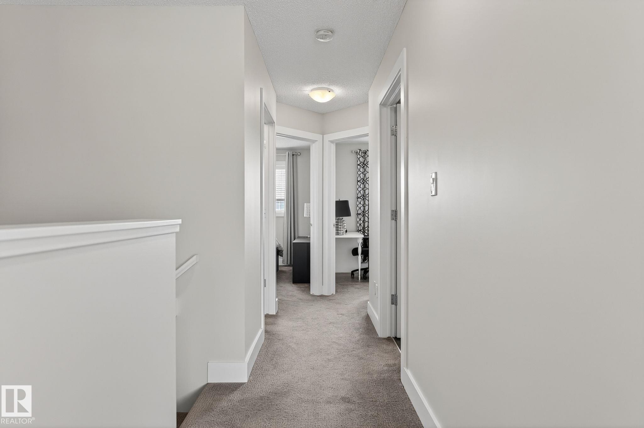 The property features a hallway with light gray carpeting and white walls, illuminated by an overhead light fixture - 9084 Rosenthal Link, Edmonton, AB - Indoor Photo Showing Other Room