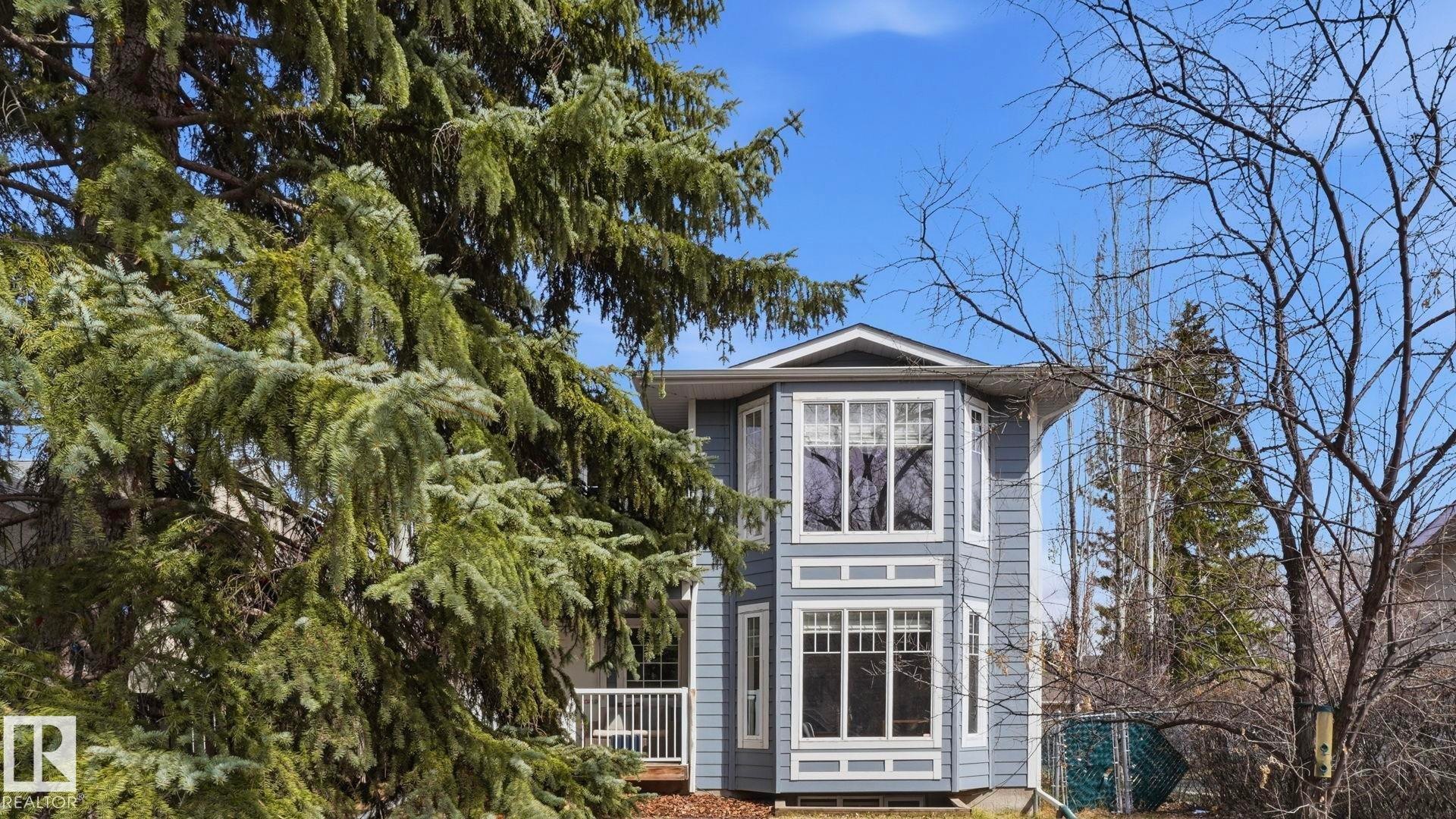Blue siding exterior with a prominent two-story bay window feature, white window trim, and white deck railing - 7235 112 Street, Edmonton, AB - Outdoor