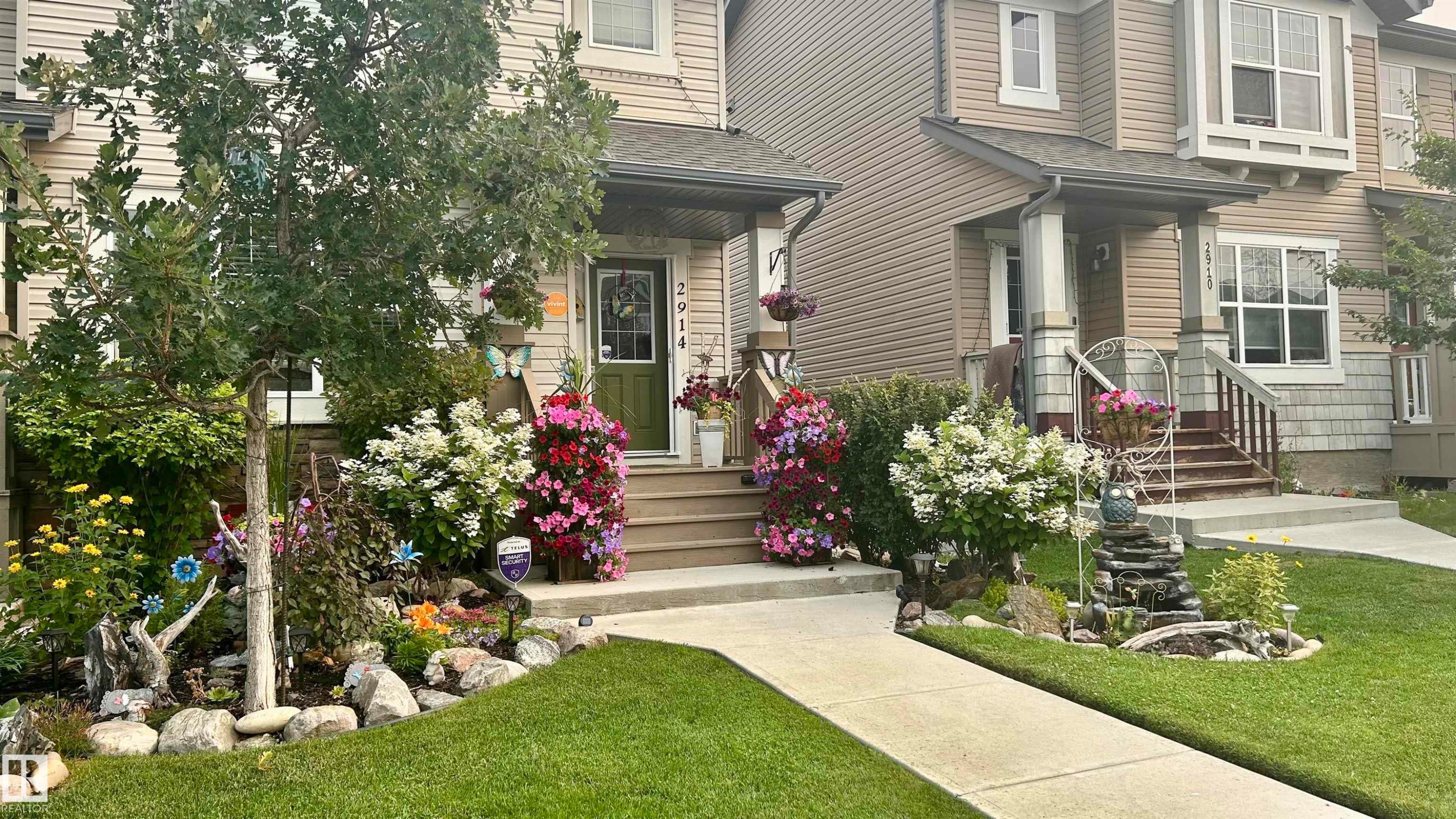 The property features a well-maintained lawn, a concrete pathway, and a front garden with diverse plantings and a mature tree - 2914 18A Avenue, Edmonton, AB - Outdoor With Facade