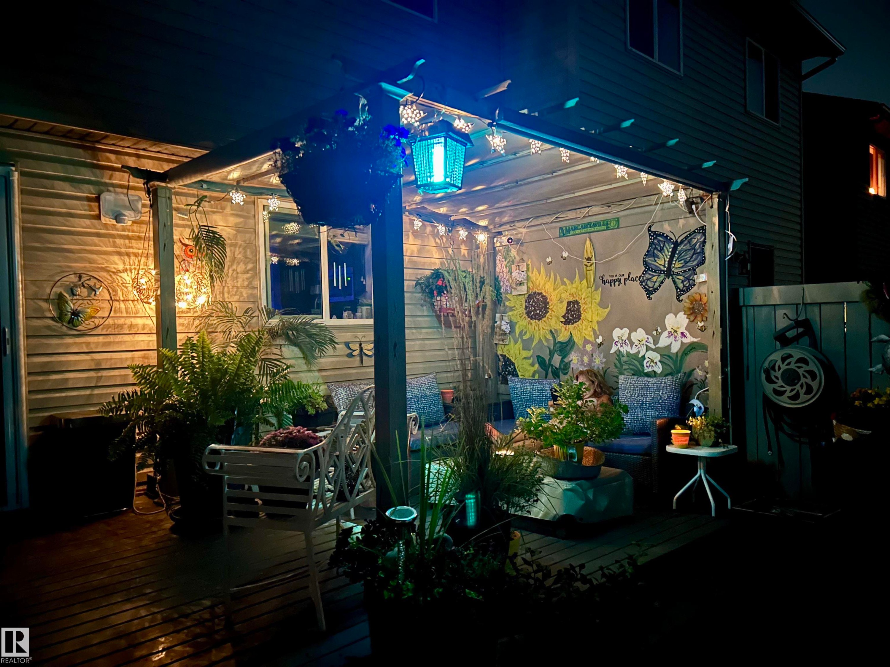 The property features an inviting covered patio with string lighting, painted murals, and decorative plants - 2914 18A Avenue, Edmonton, AB - Outdoor