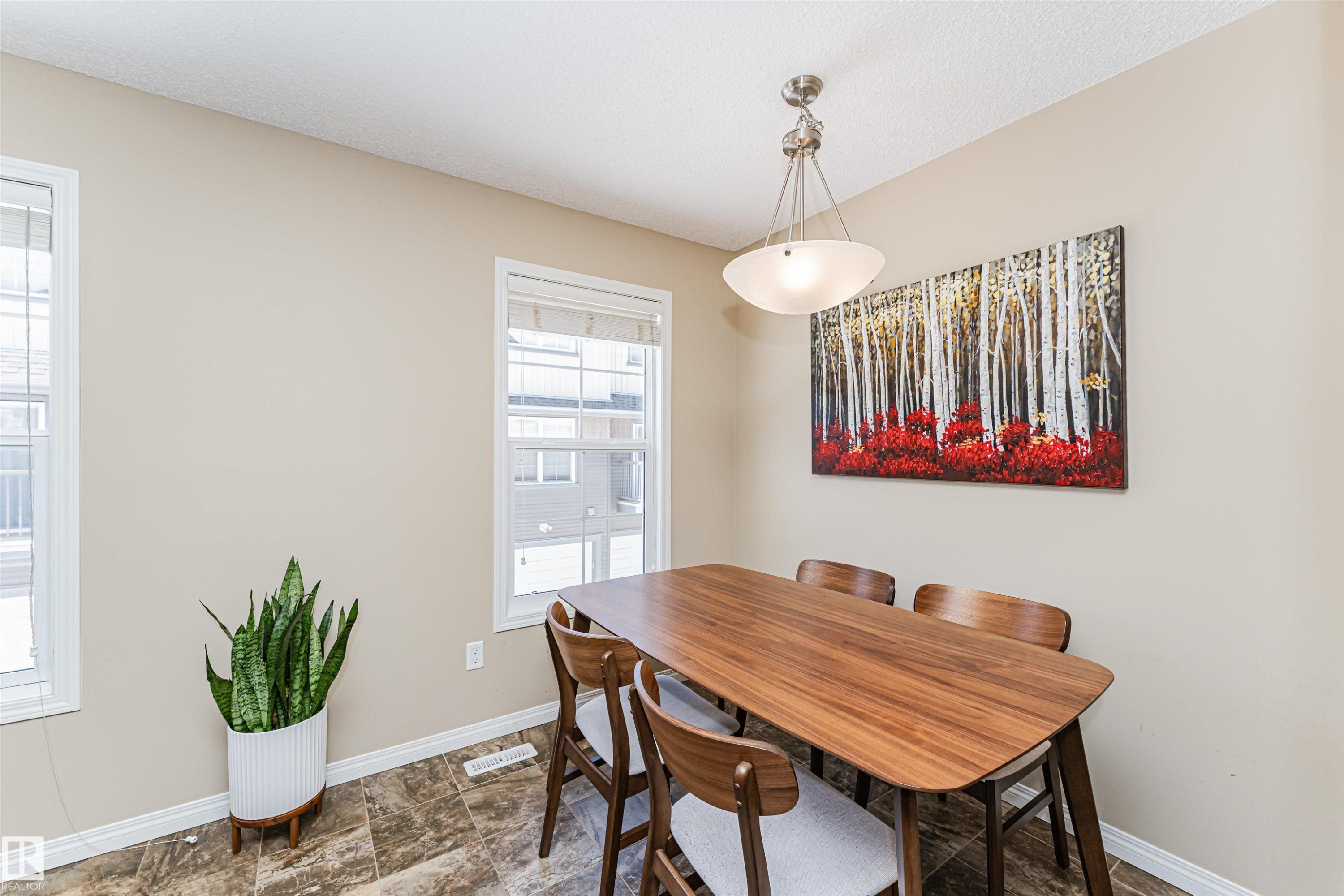 Dining area featuring two windows, a ceiling light fixture, and textured flooring - 31 4029 Orchards Drive, Edmonton, autreother - Indoor Photo Showing Dining Room