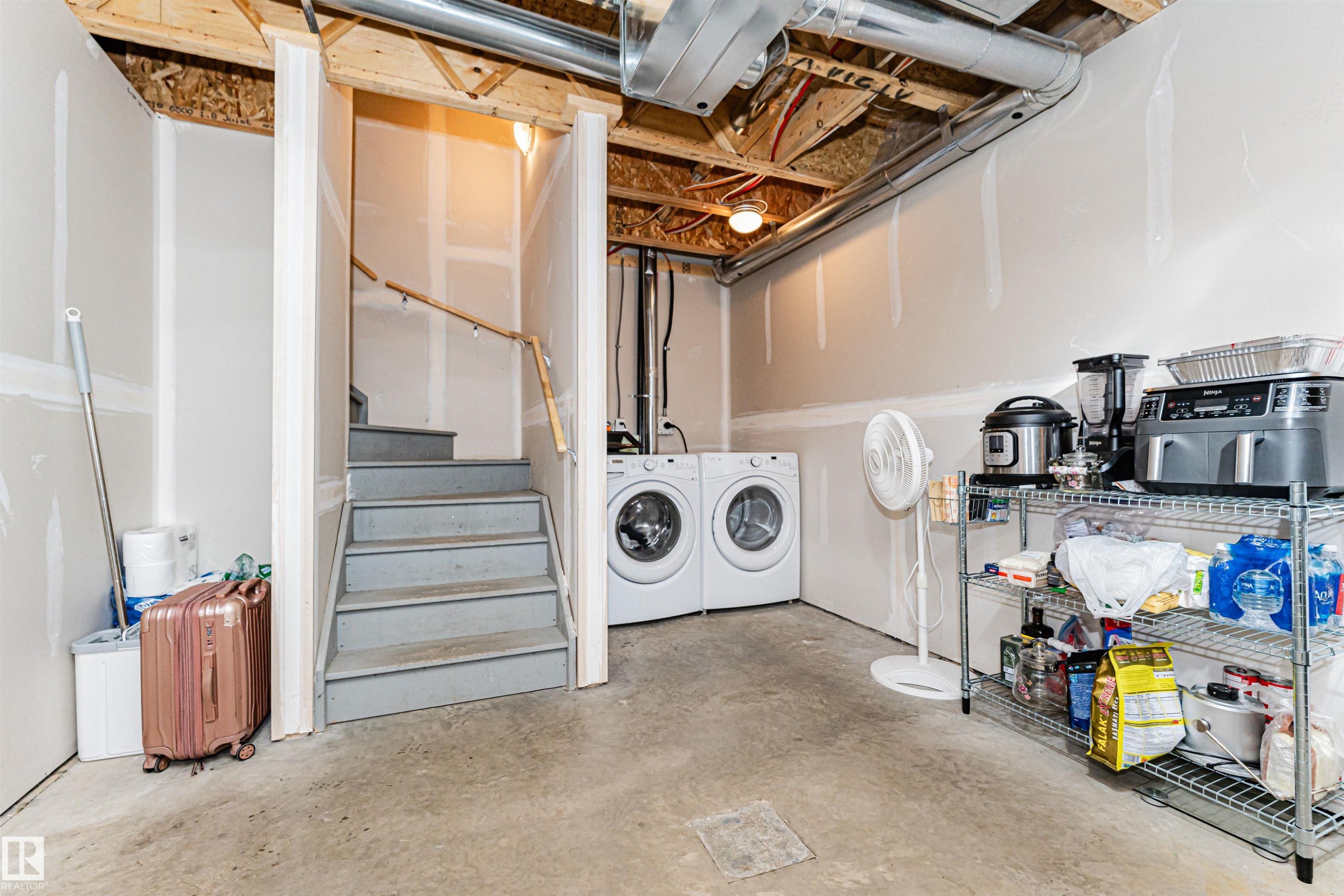 The property includes a utility area with stairs, a washing machine, and a dryer - 31 4029 Orchards Drive, Edmonton, autreother - Indoor Photo Showing Laundry Room