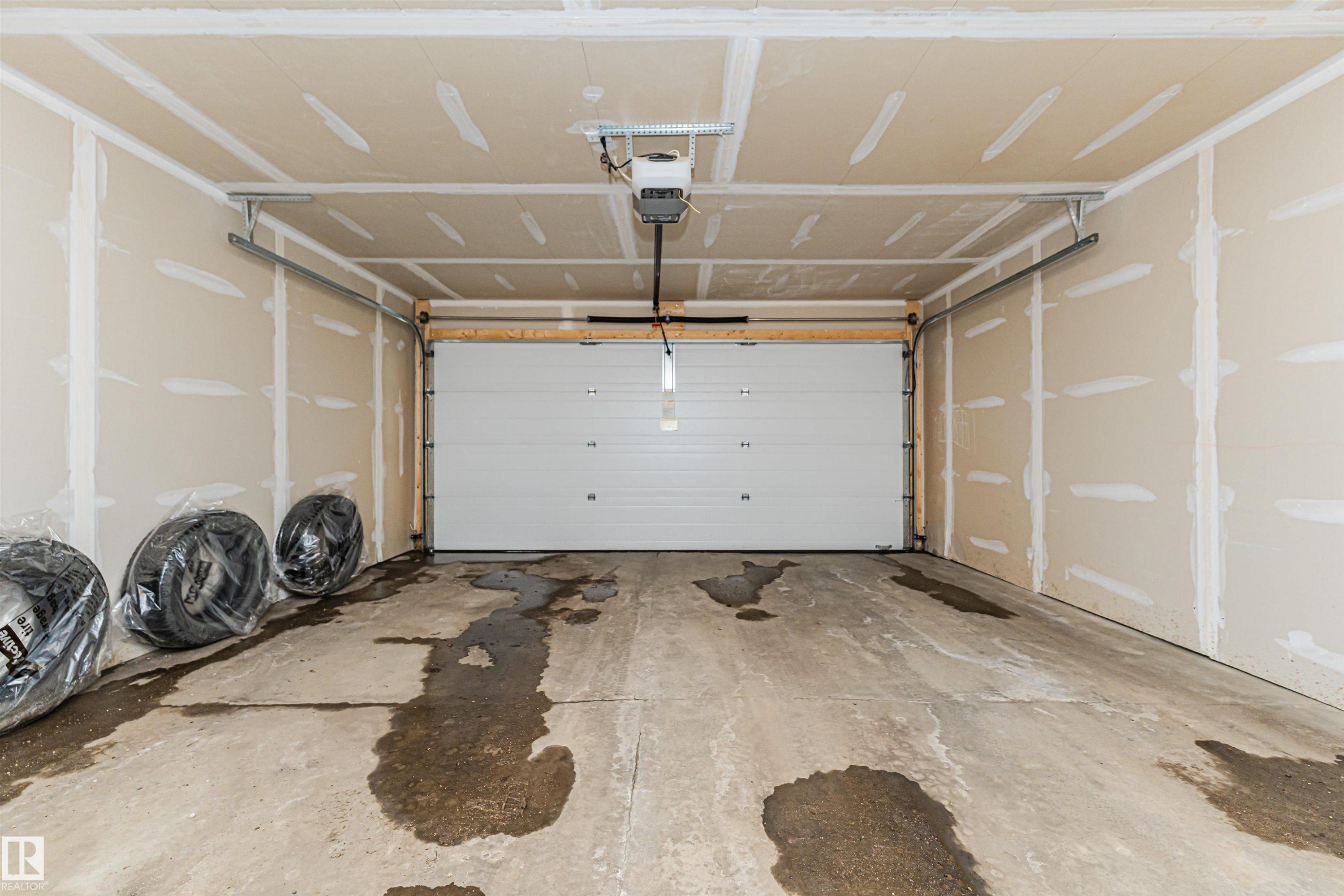 The property includes an attached garage with a concrete floor, a white overhead door, and a garage door opener - 31 4029 Orchards Drive, Edmonton, autreother - Indoor Photo Showing Garage