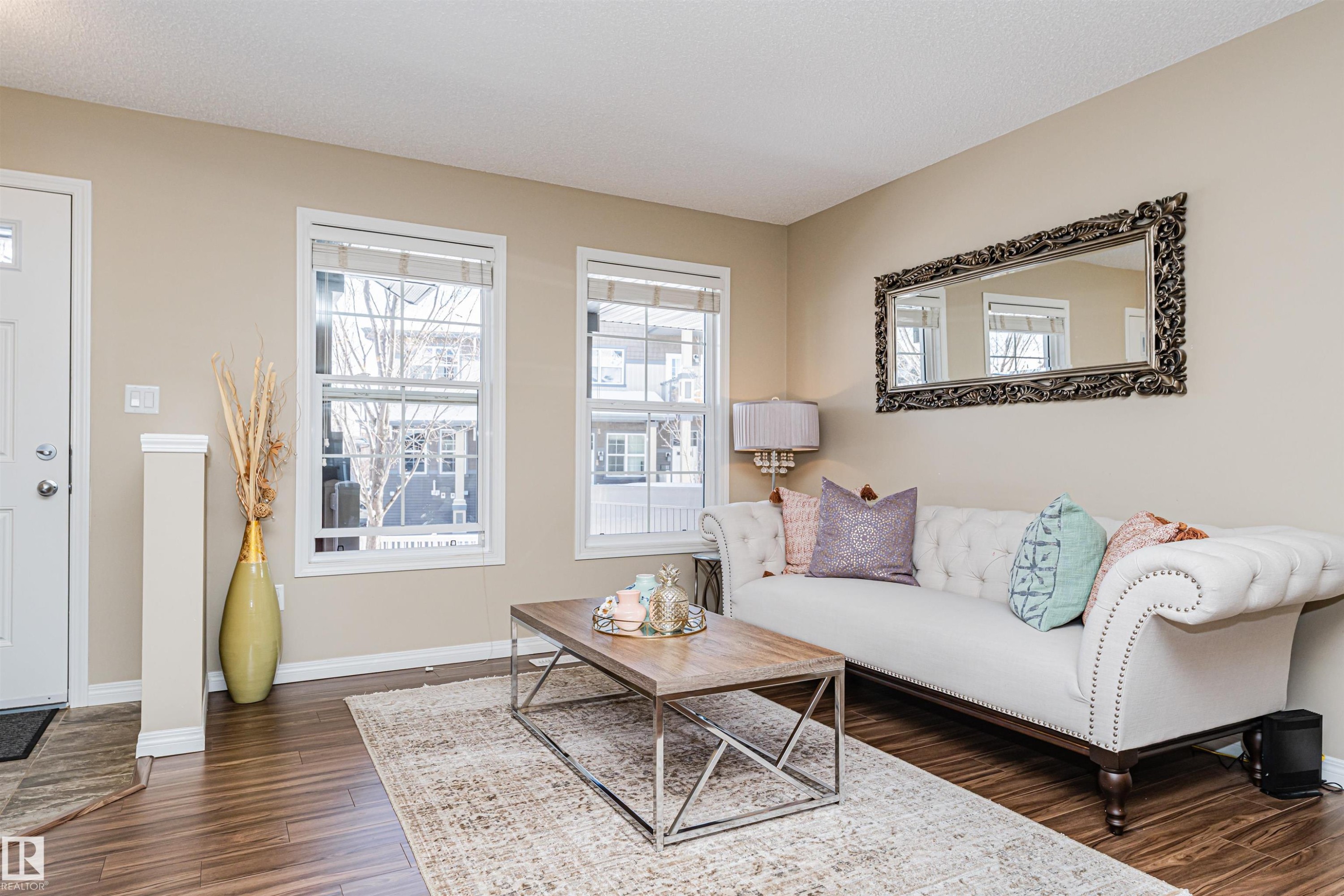 The living area features warm-toned walls, dark wood-style flooring, and an area rug - 31 4029 Orchards Drive, Edmonton, autreother - Indoor Photo Showing Living Room