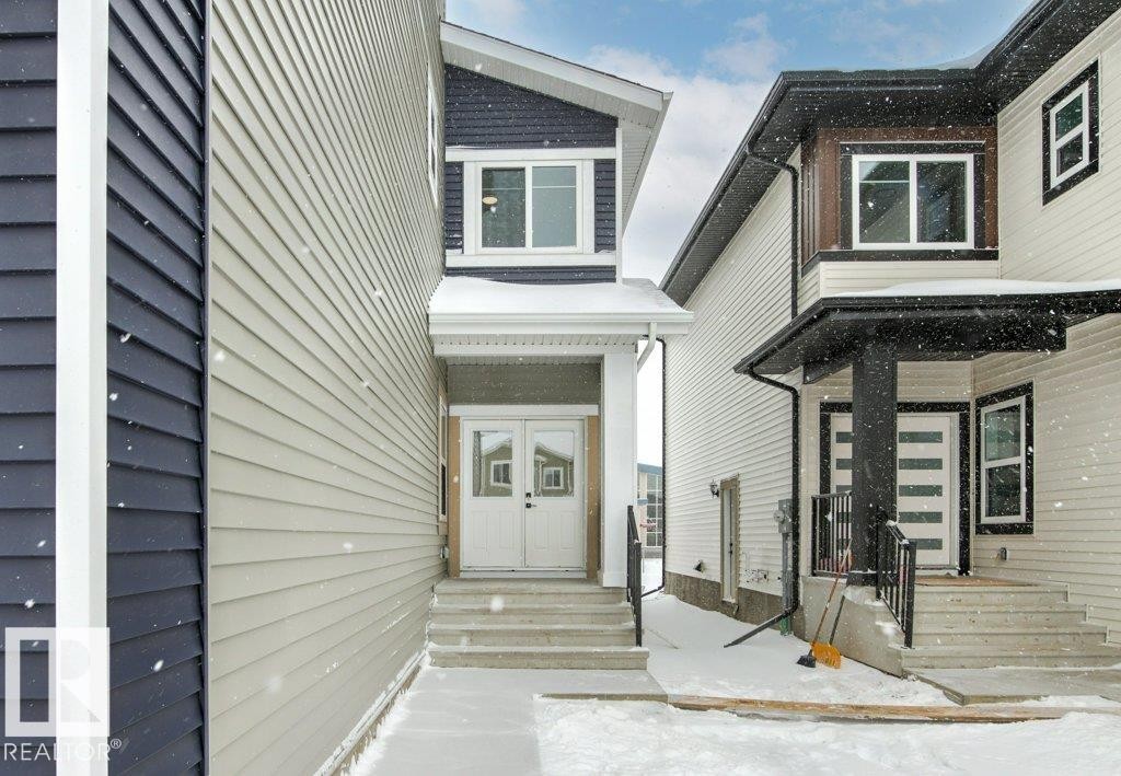 The property features a front entrance with white double doors, concrete steps, and a sheltered porch area - 5018 53 Avenue, Calmar, AB - Outdoor