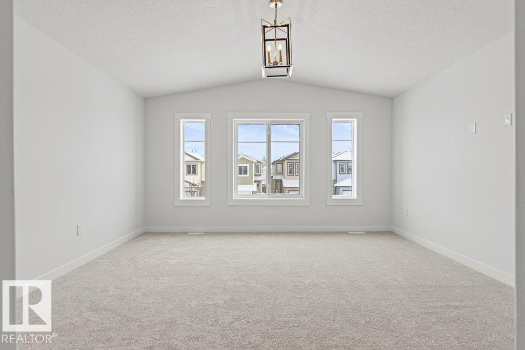 Spacious room featuring vaulted ceilings, light-colored carpeting, and three windows providing views of the neighborhood - 5018 53 Avenue, Calmar, AB - Indoor Photo Showing Other Room