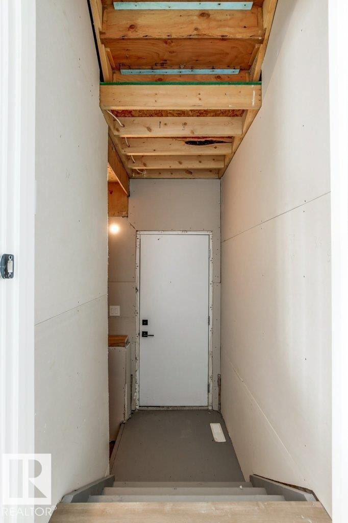 Interior view of a staircase leading down to a landing with a white door - 5018 53 Avenue, Calmar, AB - Indoor