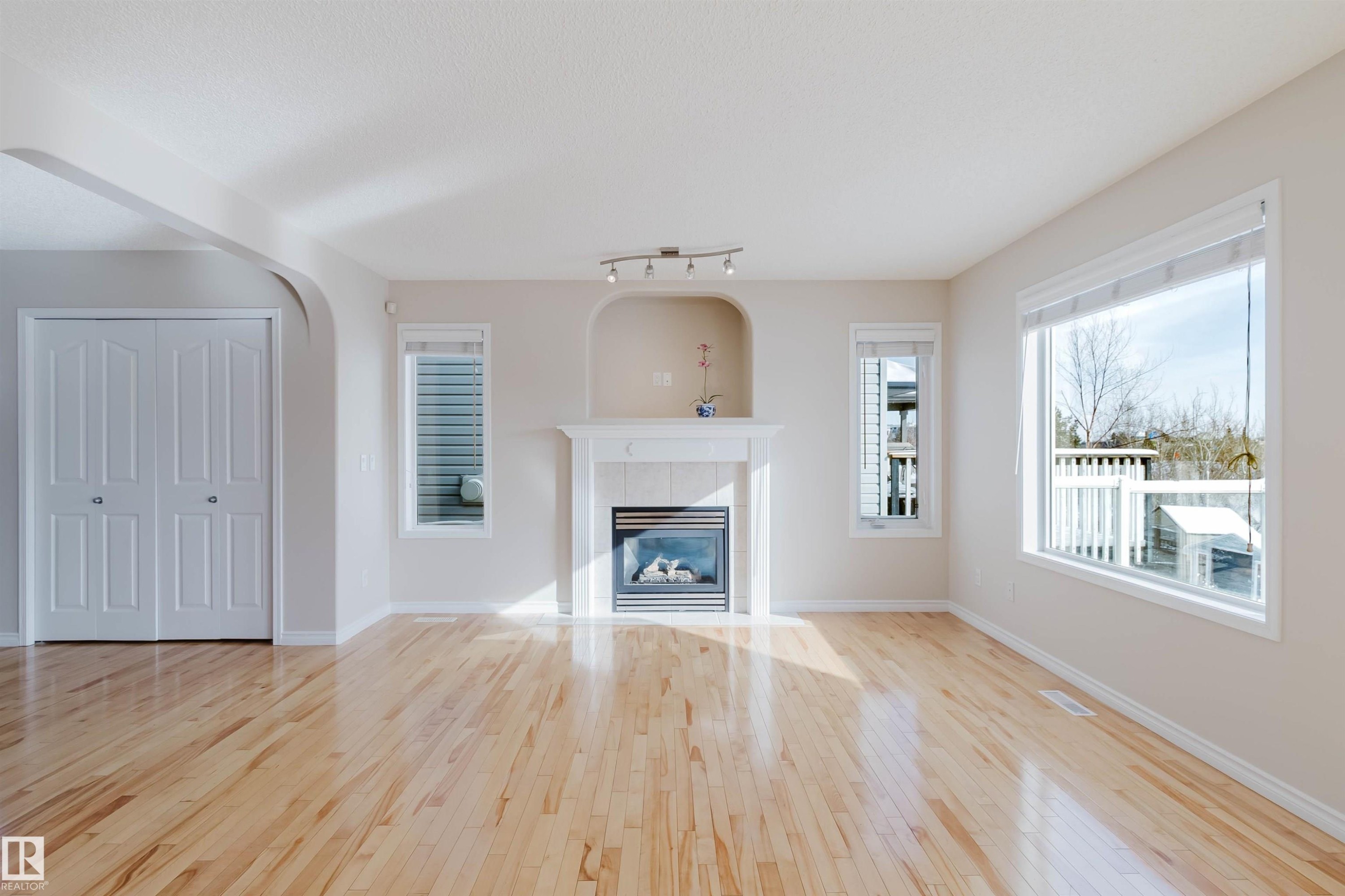 The living room features hardwood floors, a fireplace with a white mantel and tiled surround, and windows providing natural light - 1135 112 Street, Edmonton, AB - Indoor Photo Showing Living Room With Fireplace