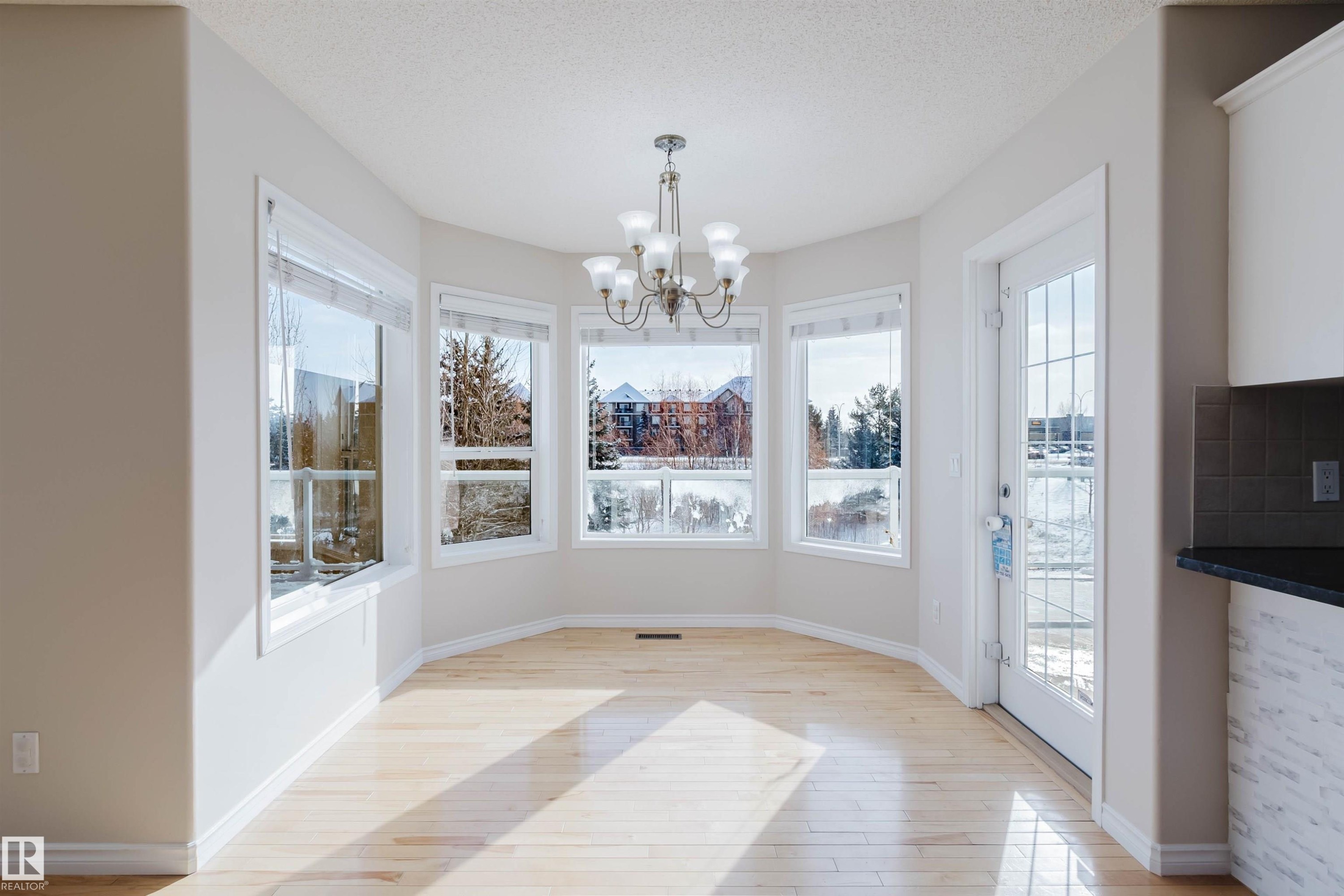 Dining area featuring light-toned hardwood floors, a bay window with five individual windows, and a glass-paned door - 1135 112 Street, Edmonton, AB - Indoor Photo Showing Other Room