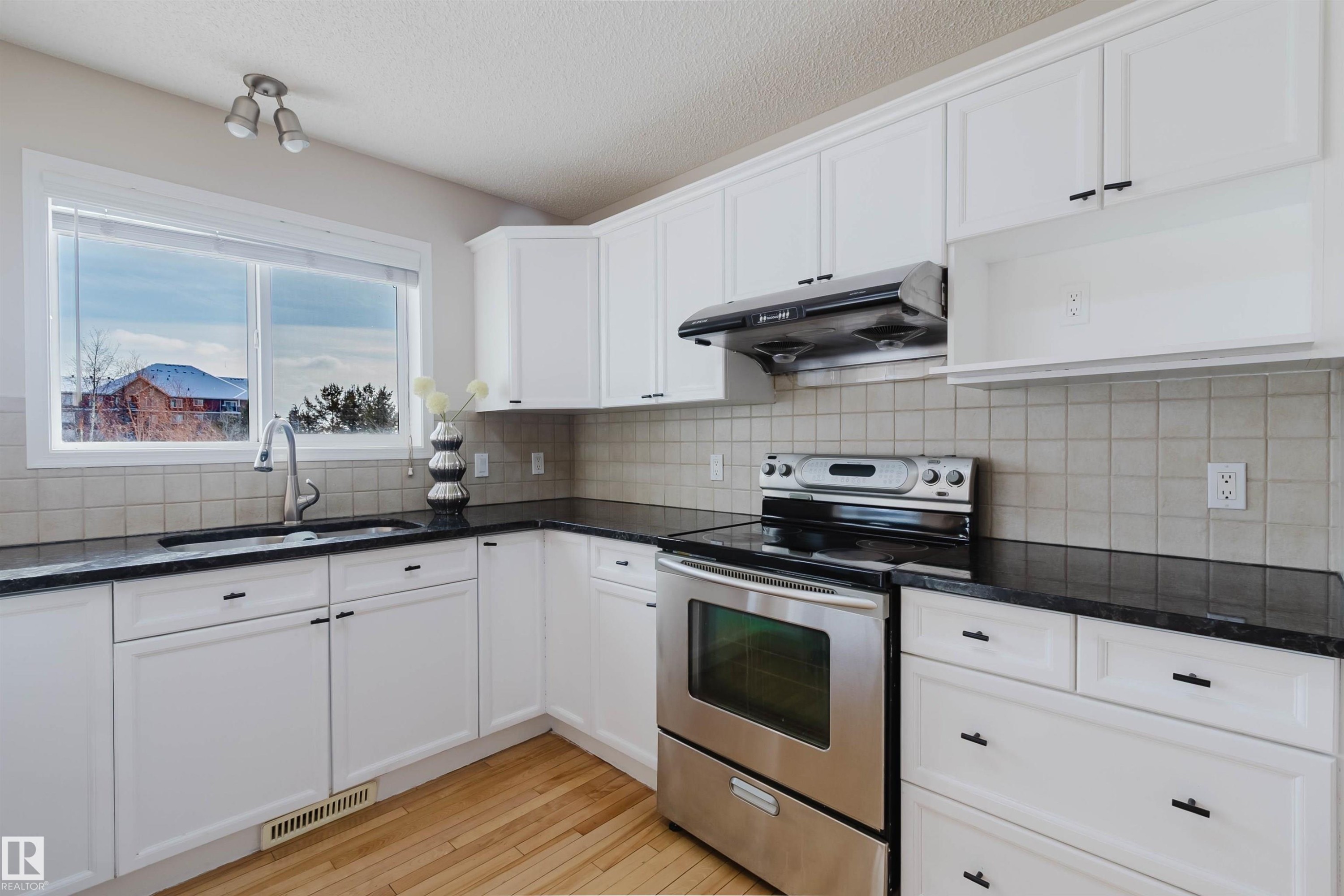 This kitchen features white cabinetry, dark countertops, and a tiled backsplash - 1135 112 Street, Edmonton, AB - Indoor Photo Showing Kitchen With Double Sink
