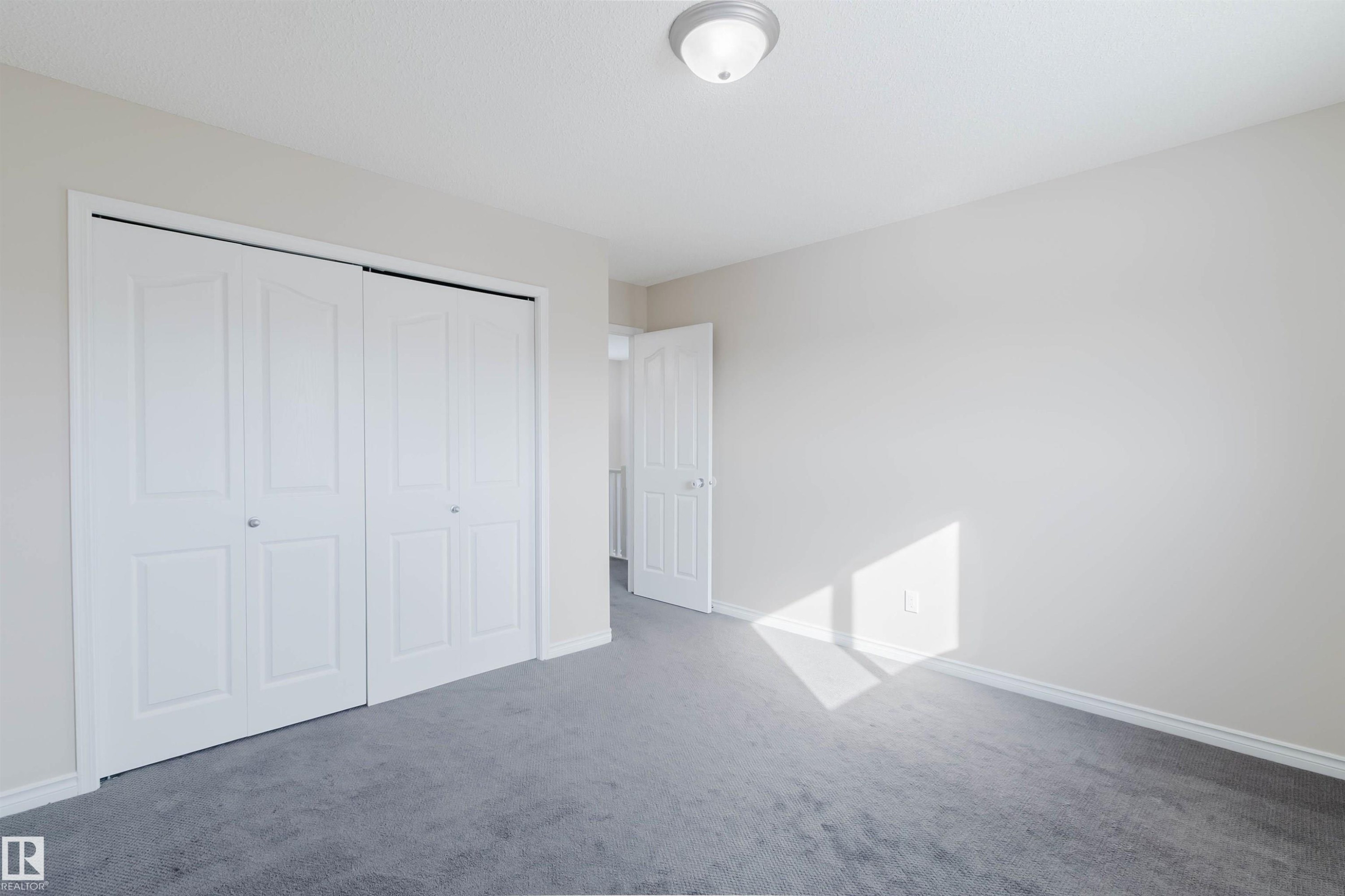 This room features neutral-toned walls, gray carpeting, and white bi-fold closet doors - 1135 112 Street, Edmonton, AB - Indoor